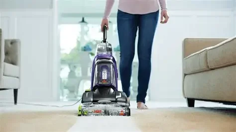Person vacuuming carpet in living room.