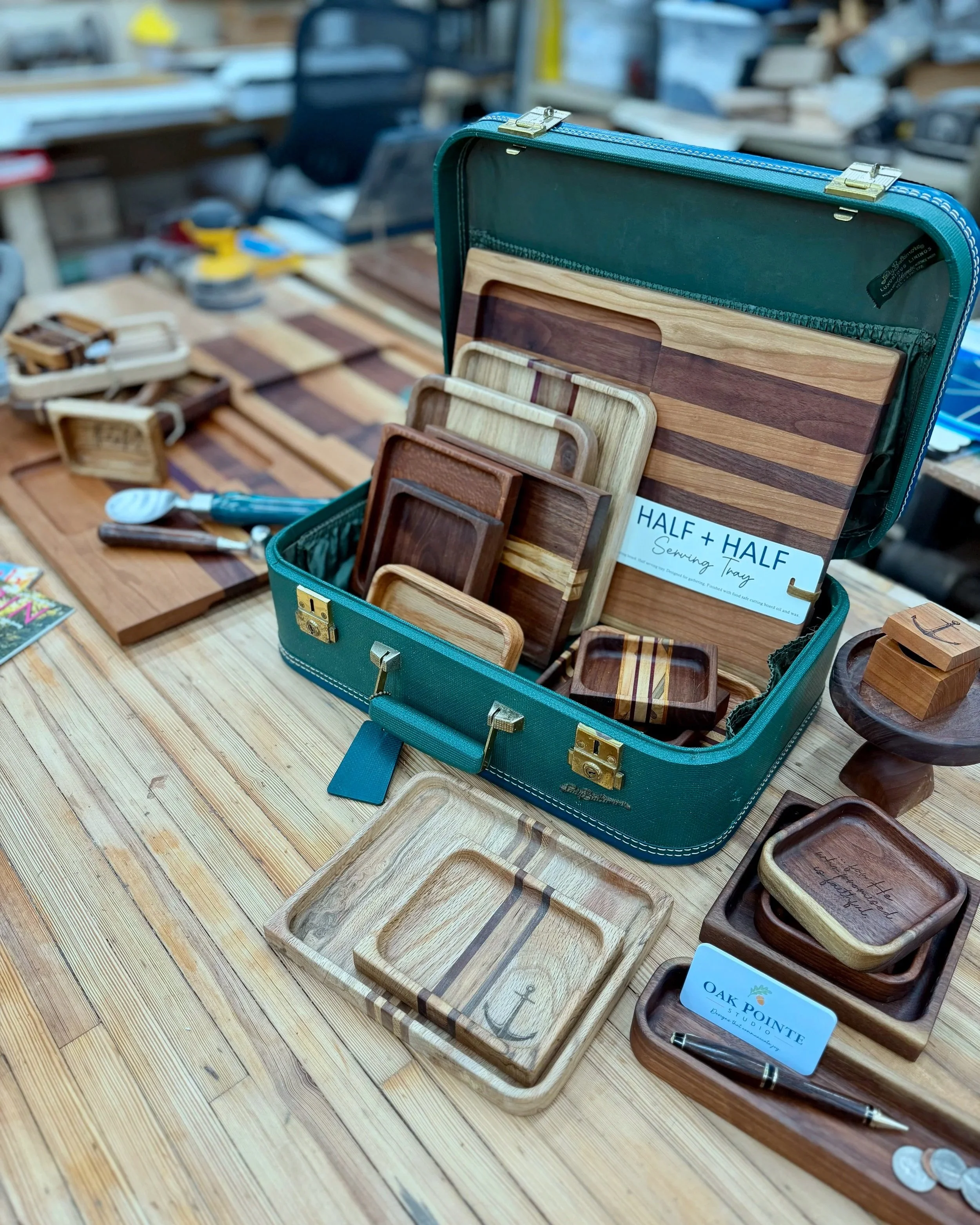 Handcrafted, wooden valet trays and serving boards in vintage suitcase on a workbench.
