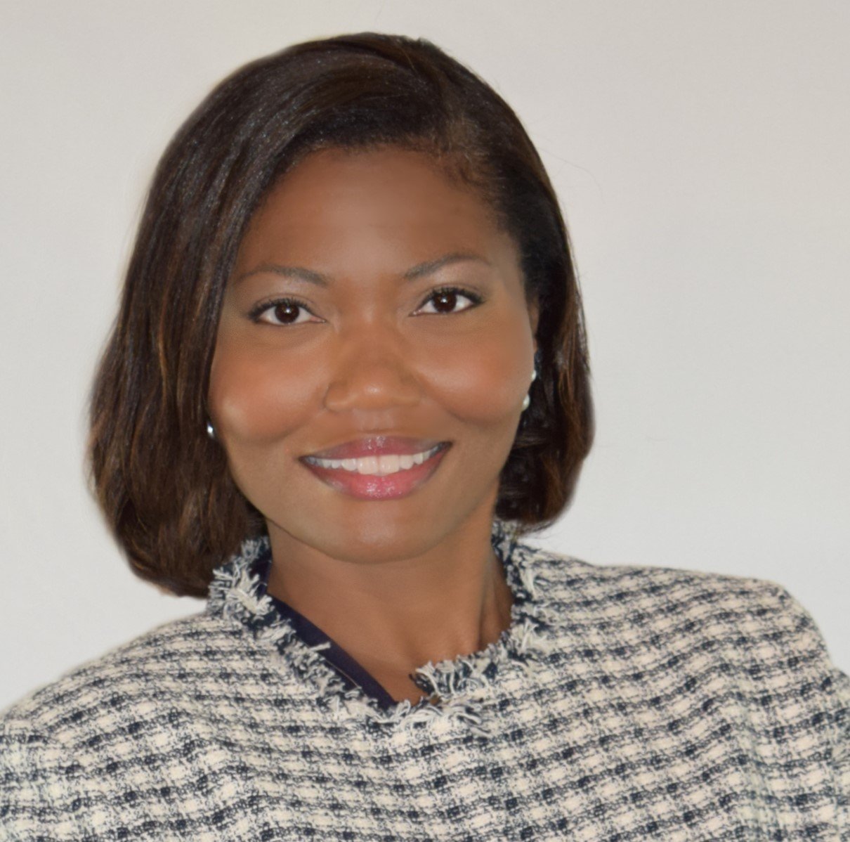 Professional headshot of an African American woman with shoulder-length hair, smiling, wearing a patterned blazer, against a neutral background.