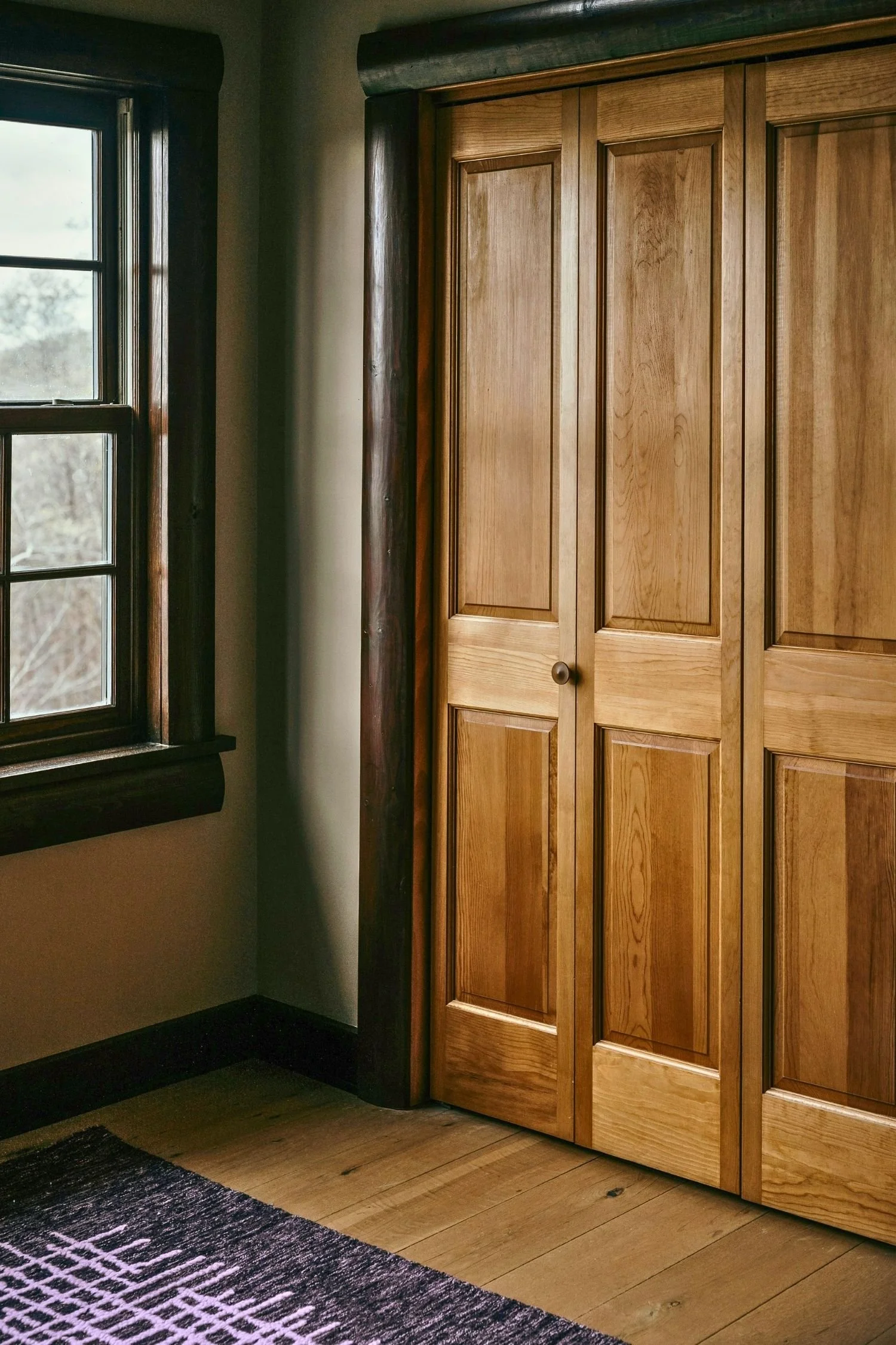 Wooden closet doors beside a window in a bedroom