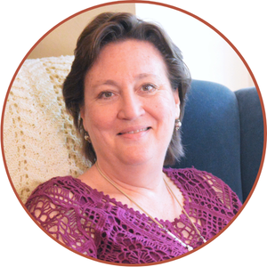 Portrait of the author seated in a chair wearing a purple patterned top