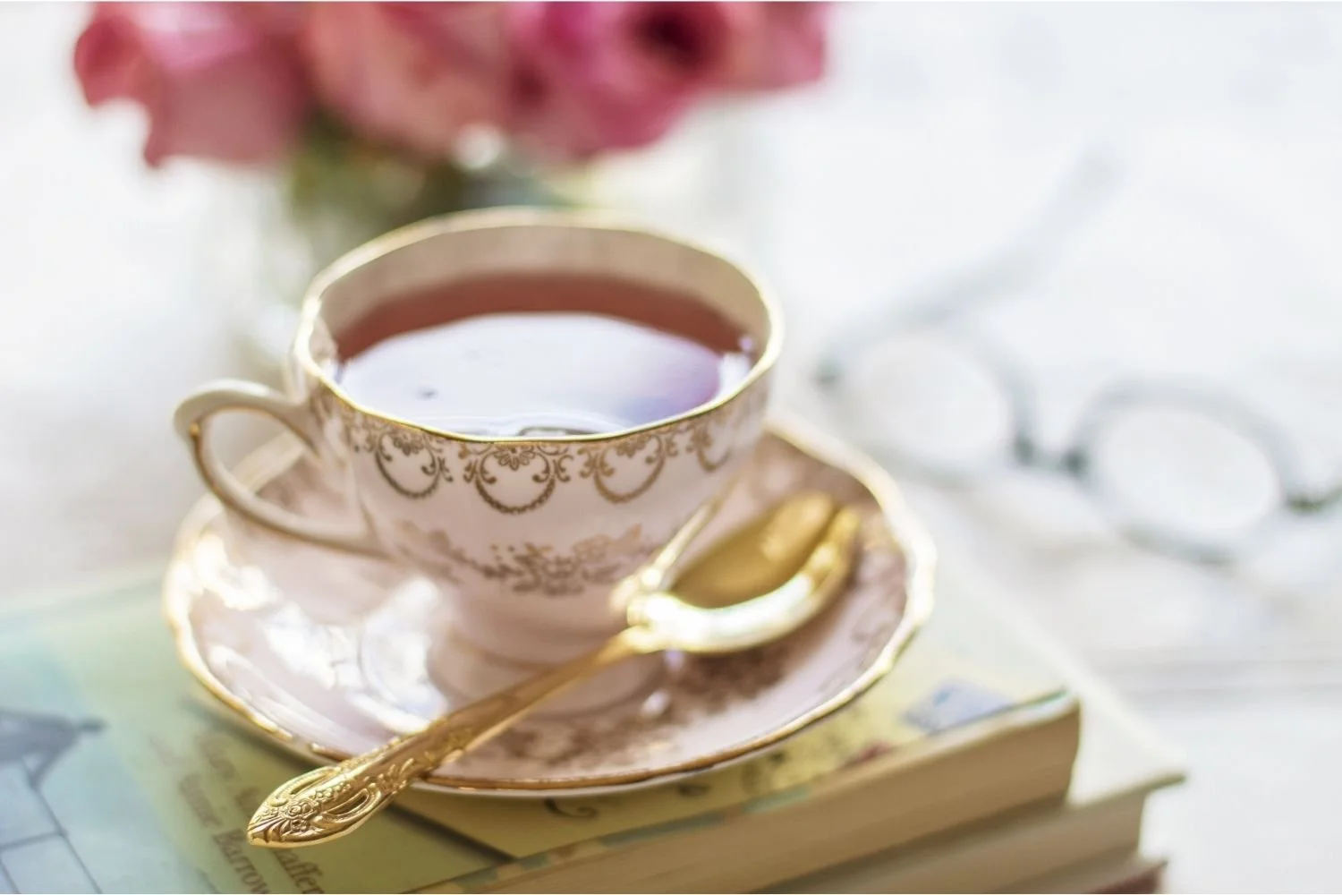 Vintage teacup with tea, gold spoon, and book, representing sentimental clutter and memories