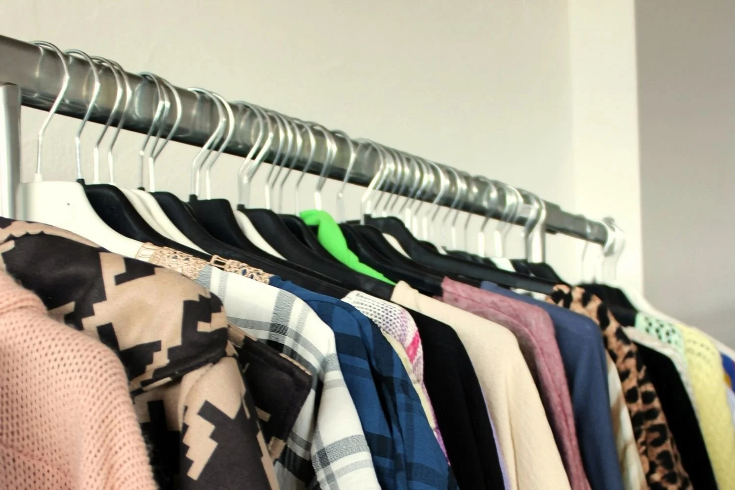 Clothes hanging in a closet on a variety of hangers