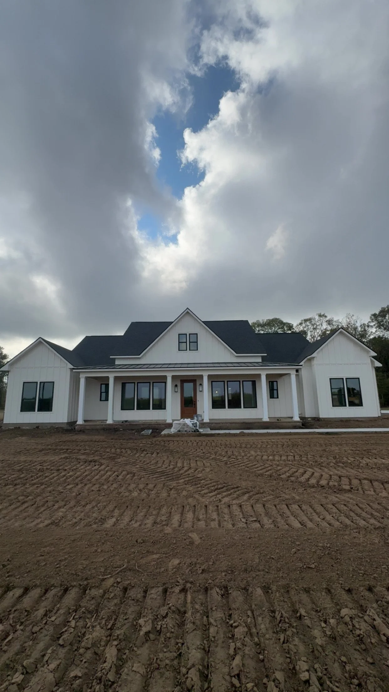 White home with a dark roof and a graded front yard