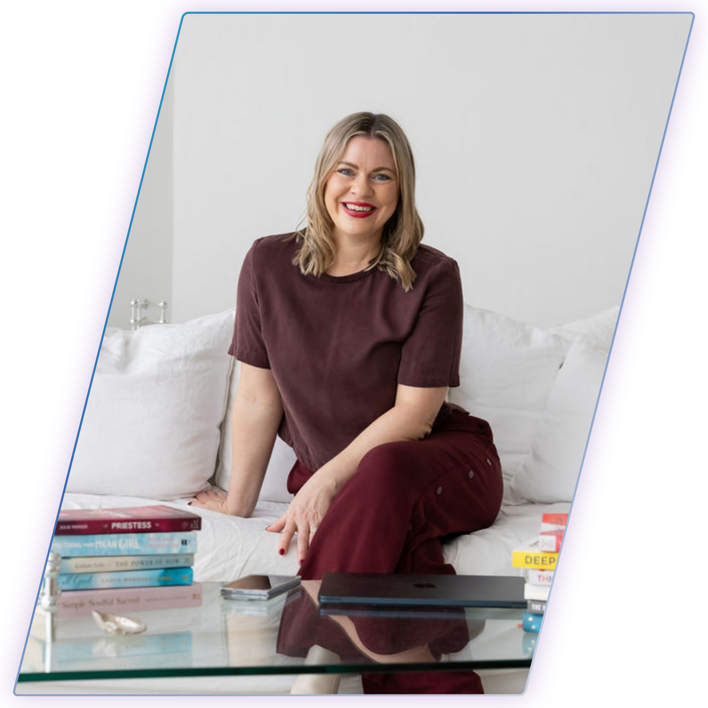 Bec Sands, author of What You Came Here to Create, sitting on a lounge with her favourite books