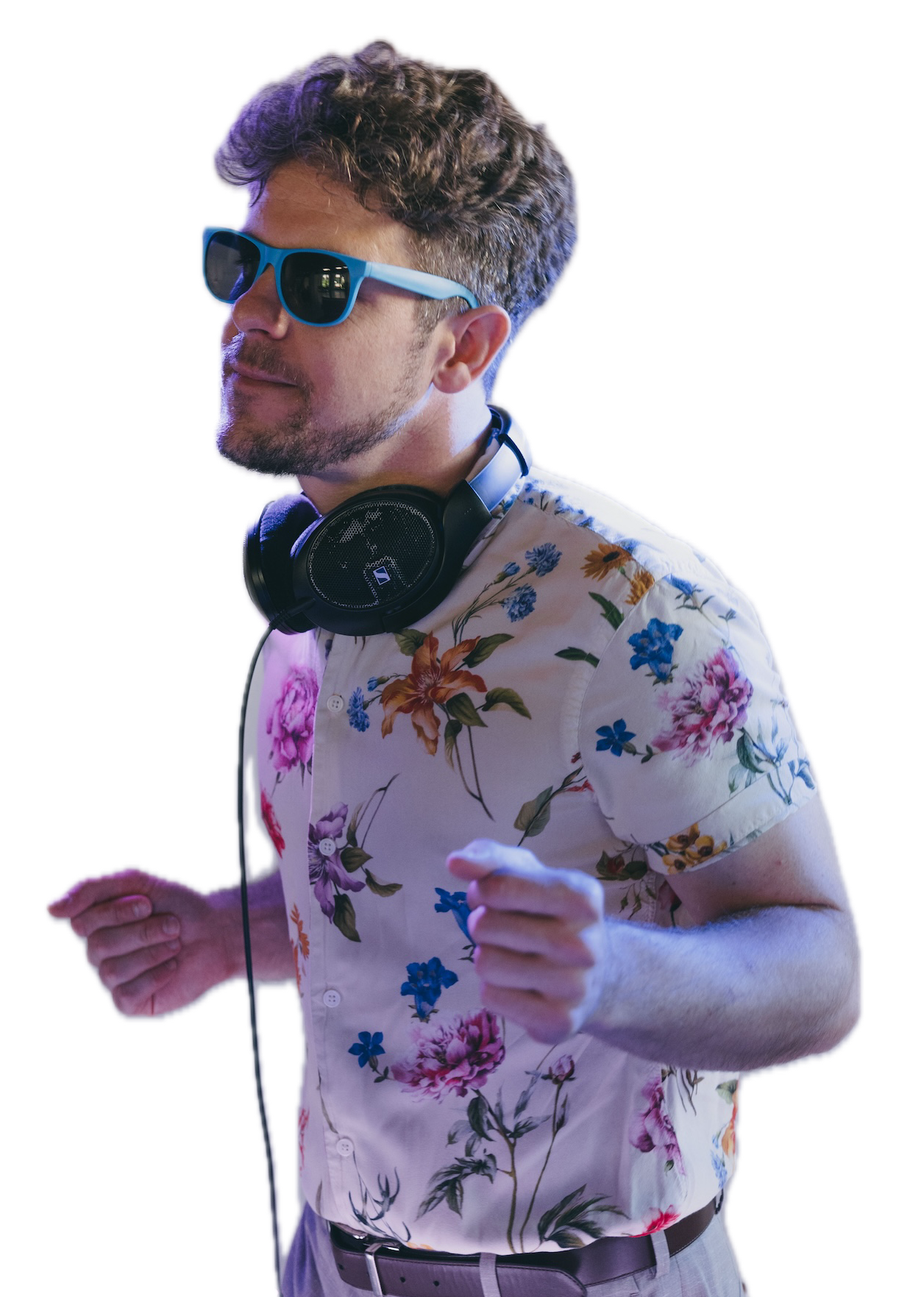 A young man with curly hair and a beard wearing blue sunglasses, a floral shirt, and headphones around his neck, appears to be dancing or jogging.