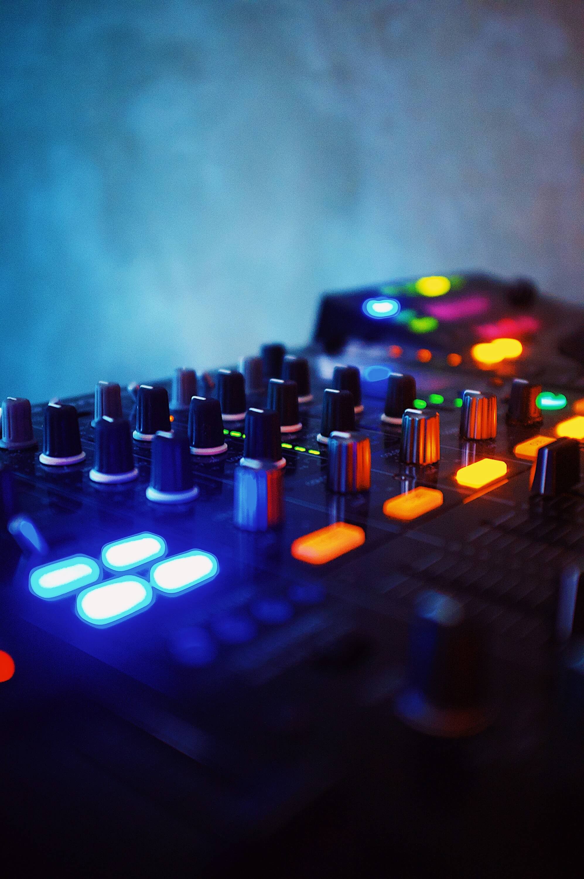 A DJ mixing music at a club with a colorful lighting setup.