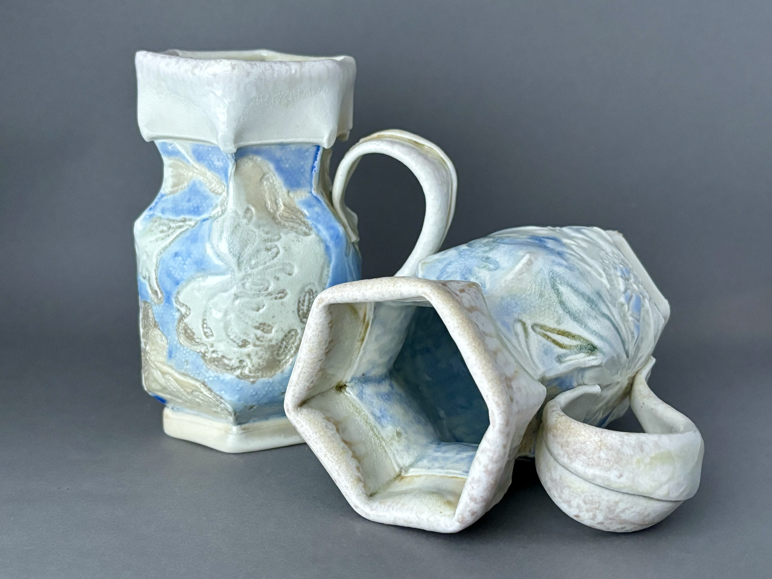 A set of small ceramic mugs with a marbled blue, white, and yellow glaze, arranged on a flat surface against a gray background.