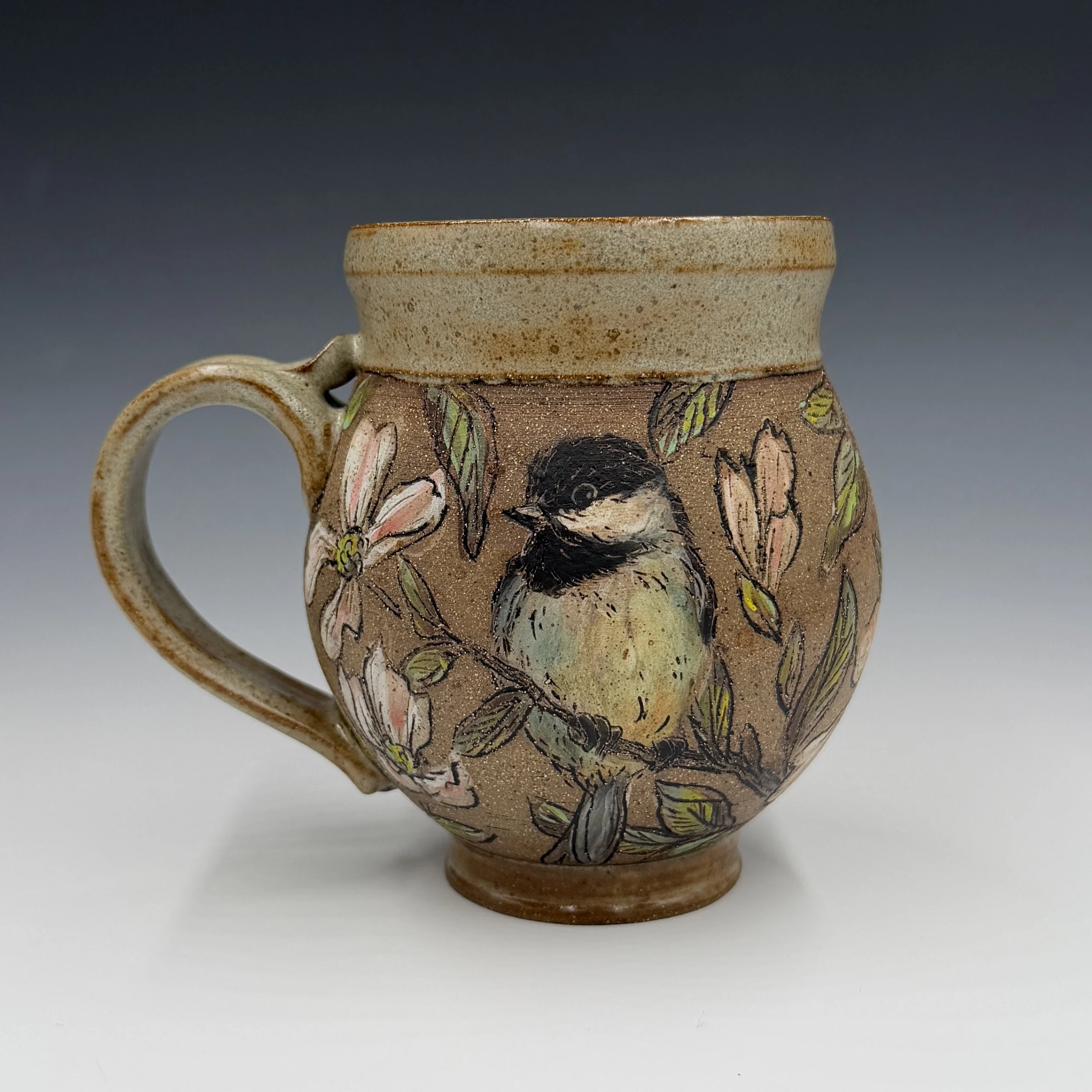 A ceramic mug with a textured, speckled cream-colored rim and a decorated body featuring a colorful floral and abstract design. - Stephanie Haines