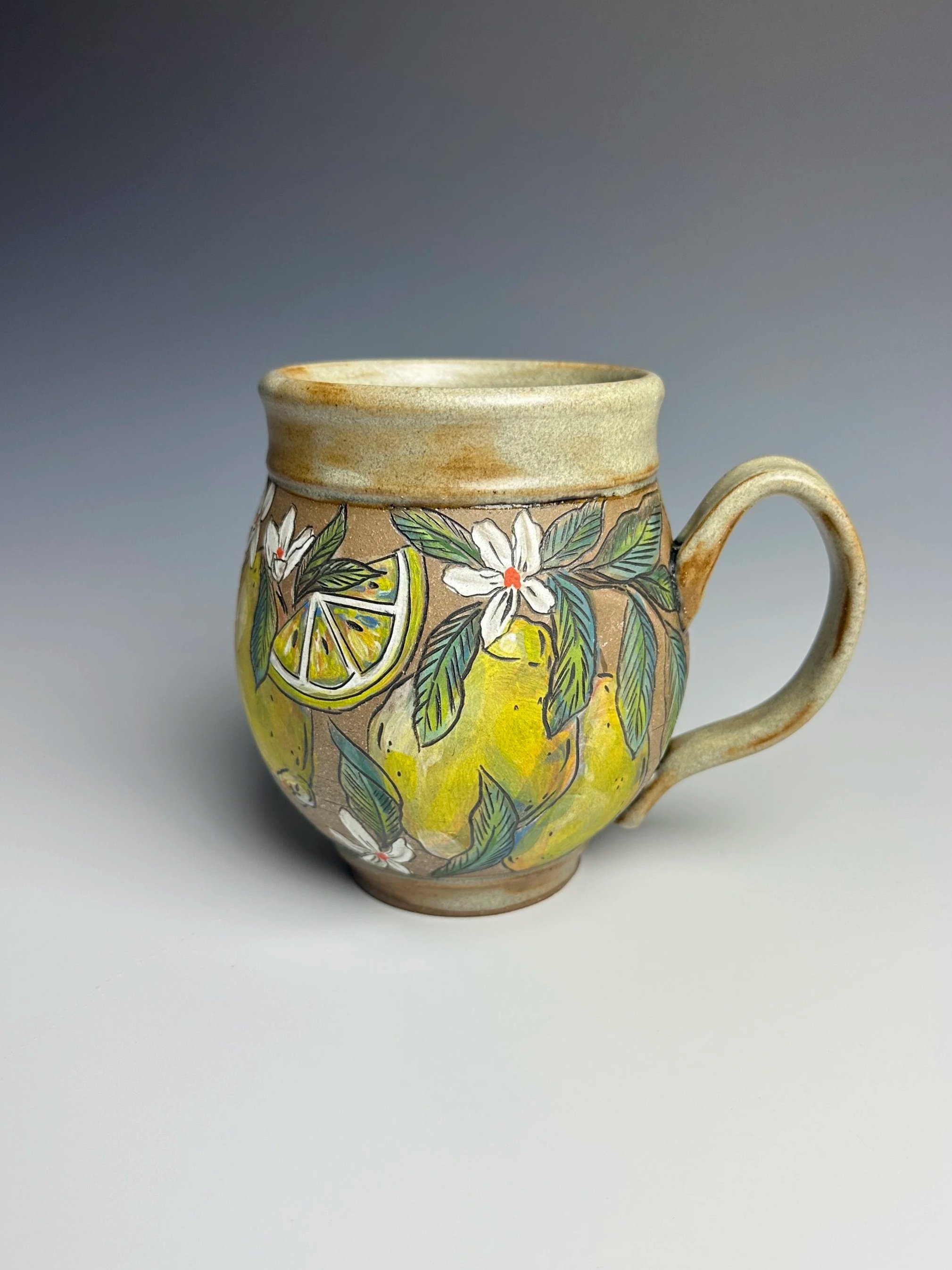 A ceramic mug with a colorful lemon and floral design on a plain background.