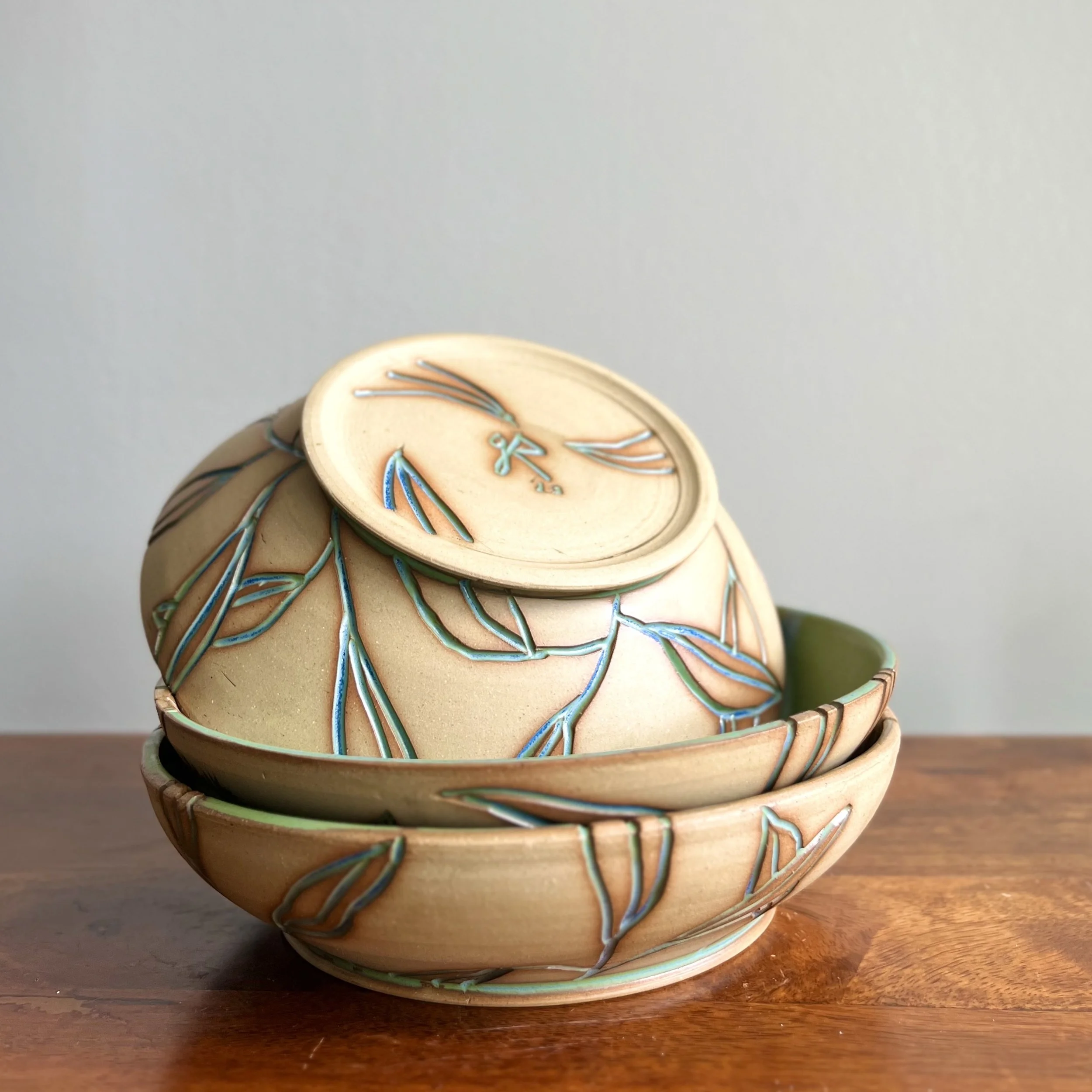 A decorative bowl with a dragonfly design, sitting on a wooden surface.