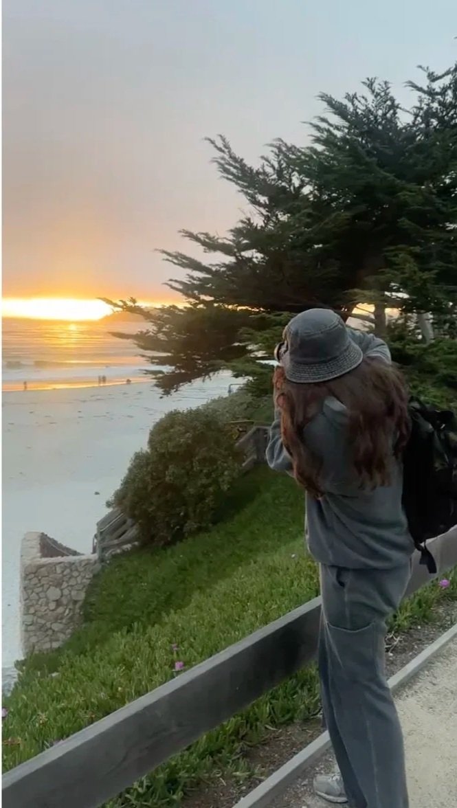 Photographer capturing a coastal sunset from a beachside path.