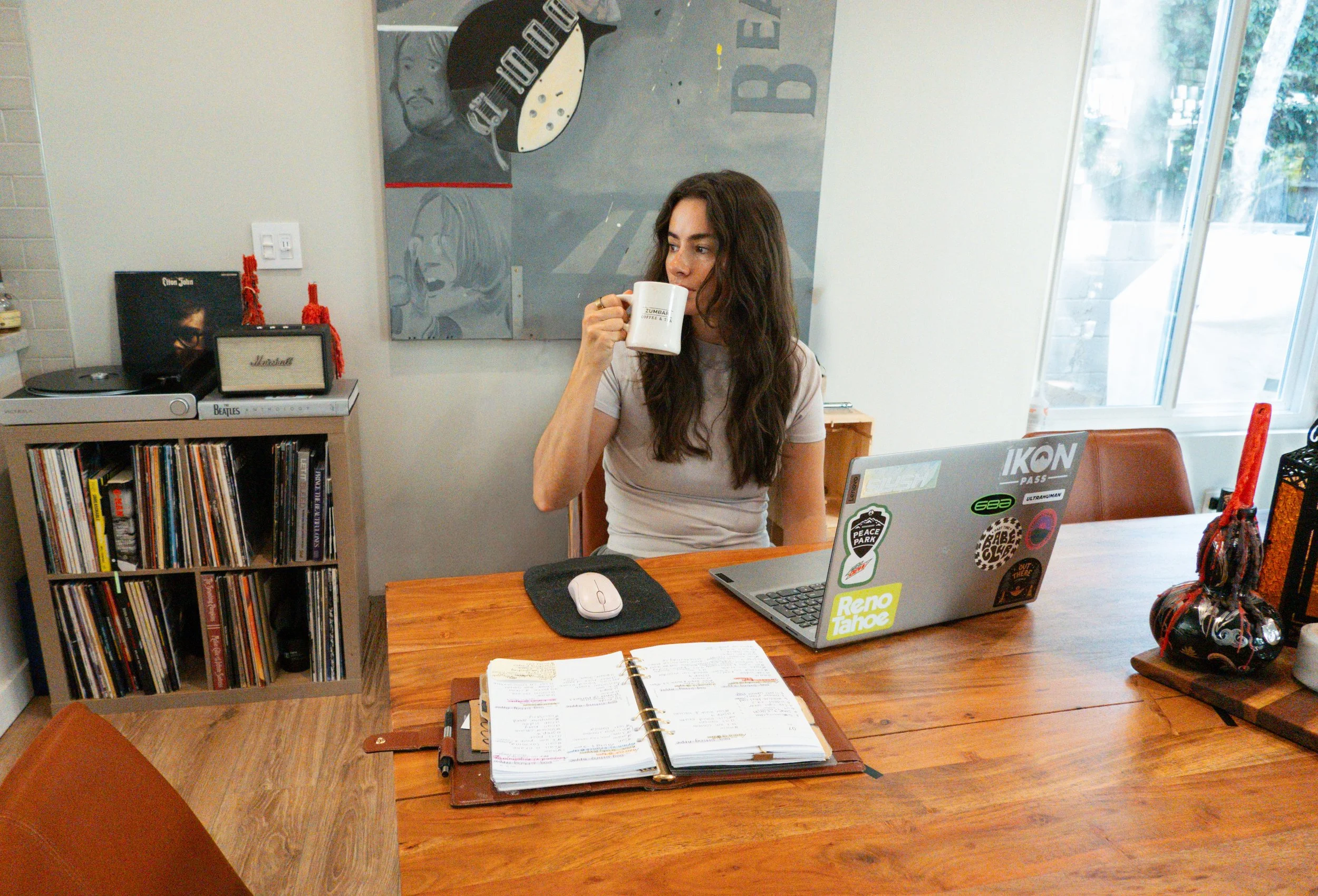 Creative strategist Rose Lee seated at a wooden table with coffee, notebook and laptop in a bright interior.