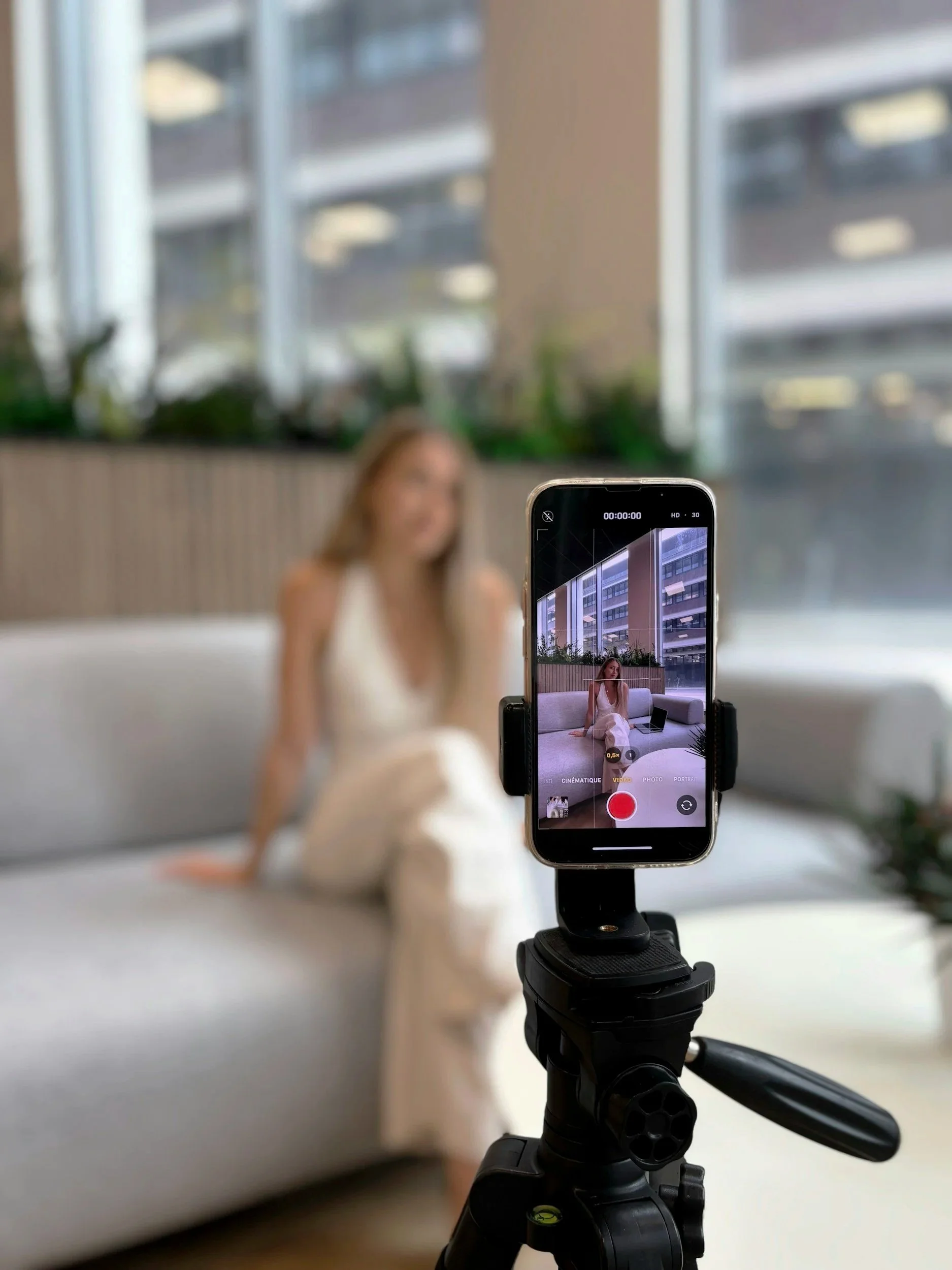 Behind-the-scenes content shoot with a smartphone on a tripod filming a person working on a laptop.