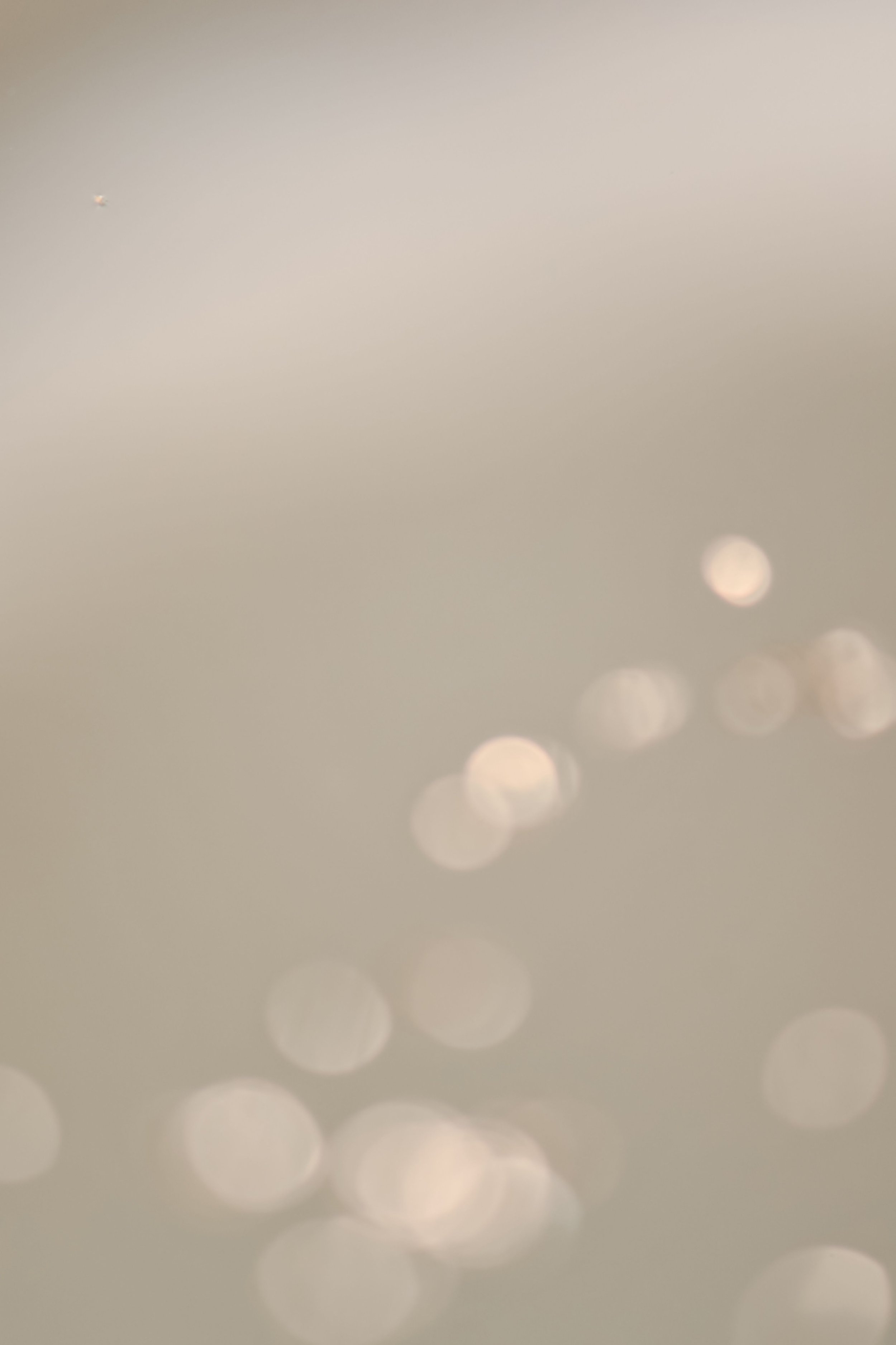 Blurred image with soft light circles, no distinct objects or details visible.