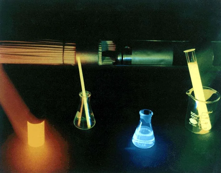 Laboratory setup with test tubes, a pipette, and a UV light illuminating the liquids.