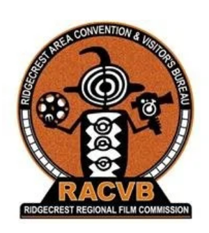 Logo for the Ridgecrest Area Convention & Visitors Bureau with a stylized insect holding film reels, featuring the text 'RACVB' and 'Ridgecrest Regional Film Commission.'