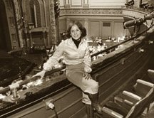 A woman sitting on the front row of a theater balcony, looking at the camera.
