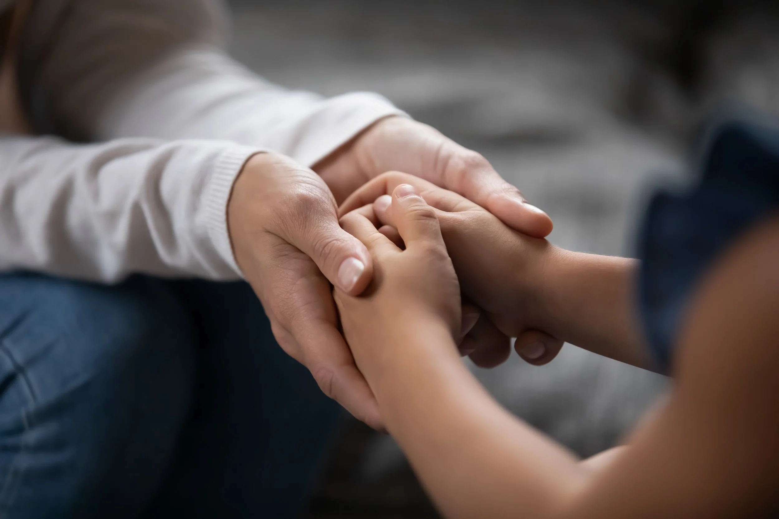 Close-up of an adult holding a child's hand gently.