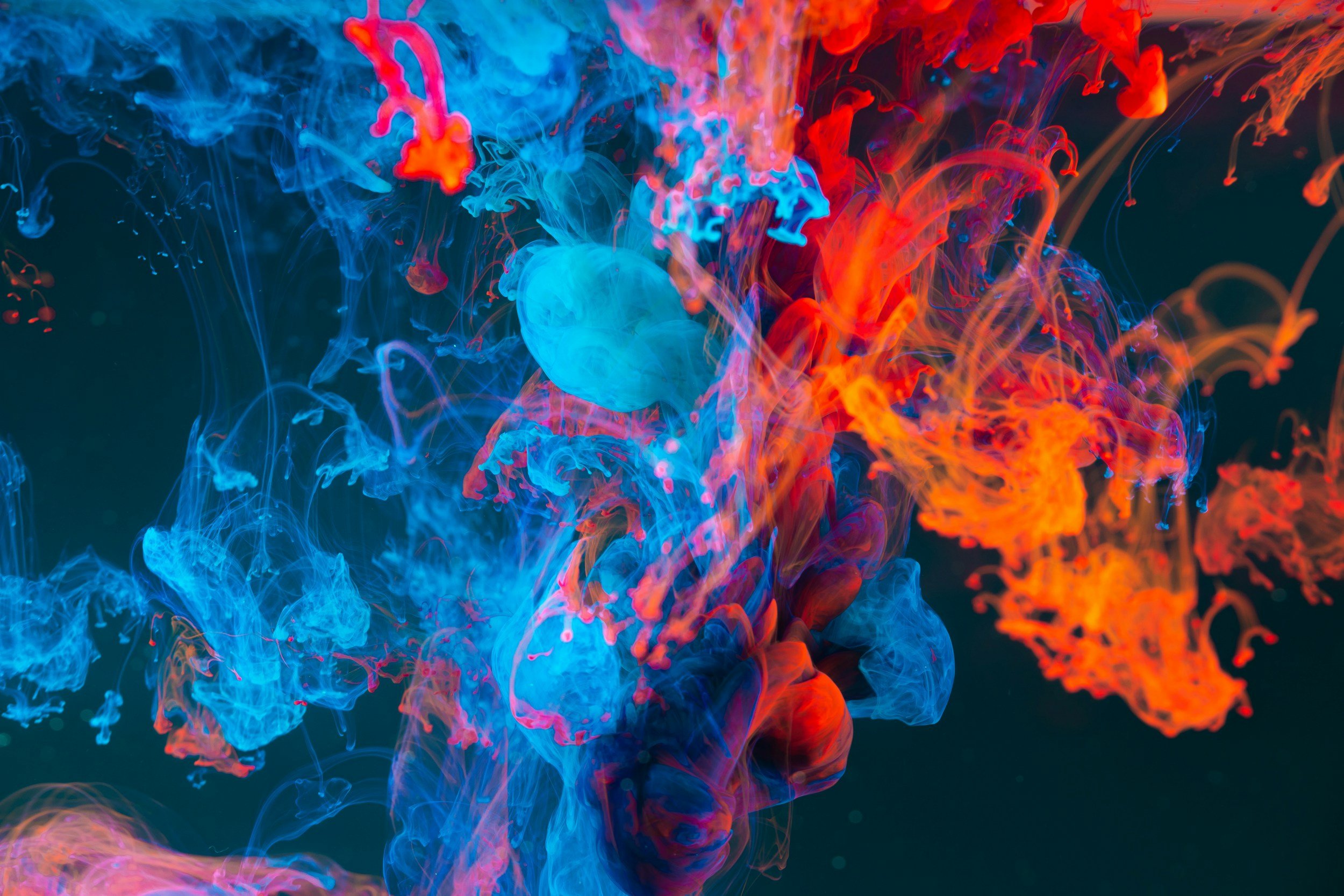 Un fondo colorido de humo o tinta en el agua en tonos azules, rojos y naranja.