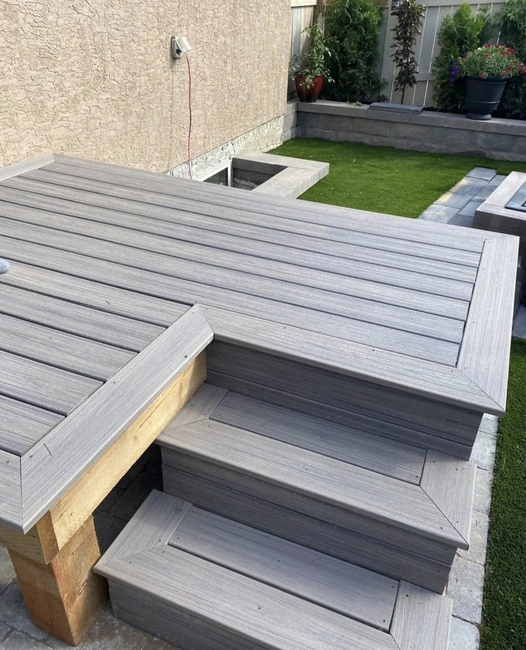 Backyards with wooden stairs, potted plants, lawn, and garden decor.