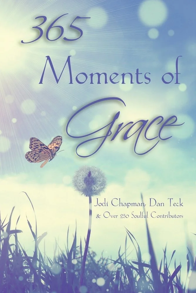 Book cover titled "365 Moments of Grace" by Jodi Chapman and Dan Teck, featuring a dandelion puff, butterfly, and sunlight with blue sky and grass in the background.