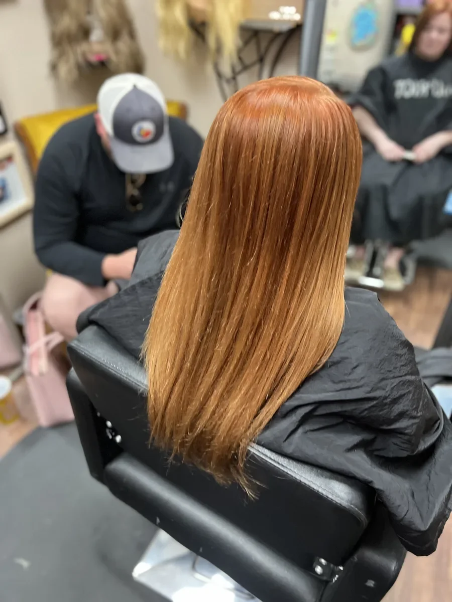 Long copper straight hair by The Hair Court in Bryan-College Station, TX.
