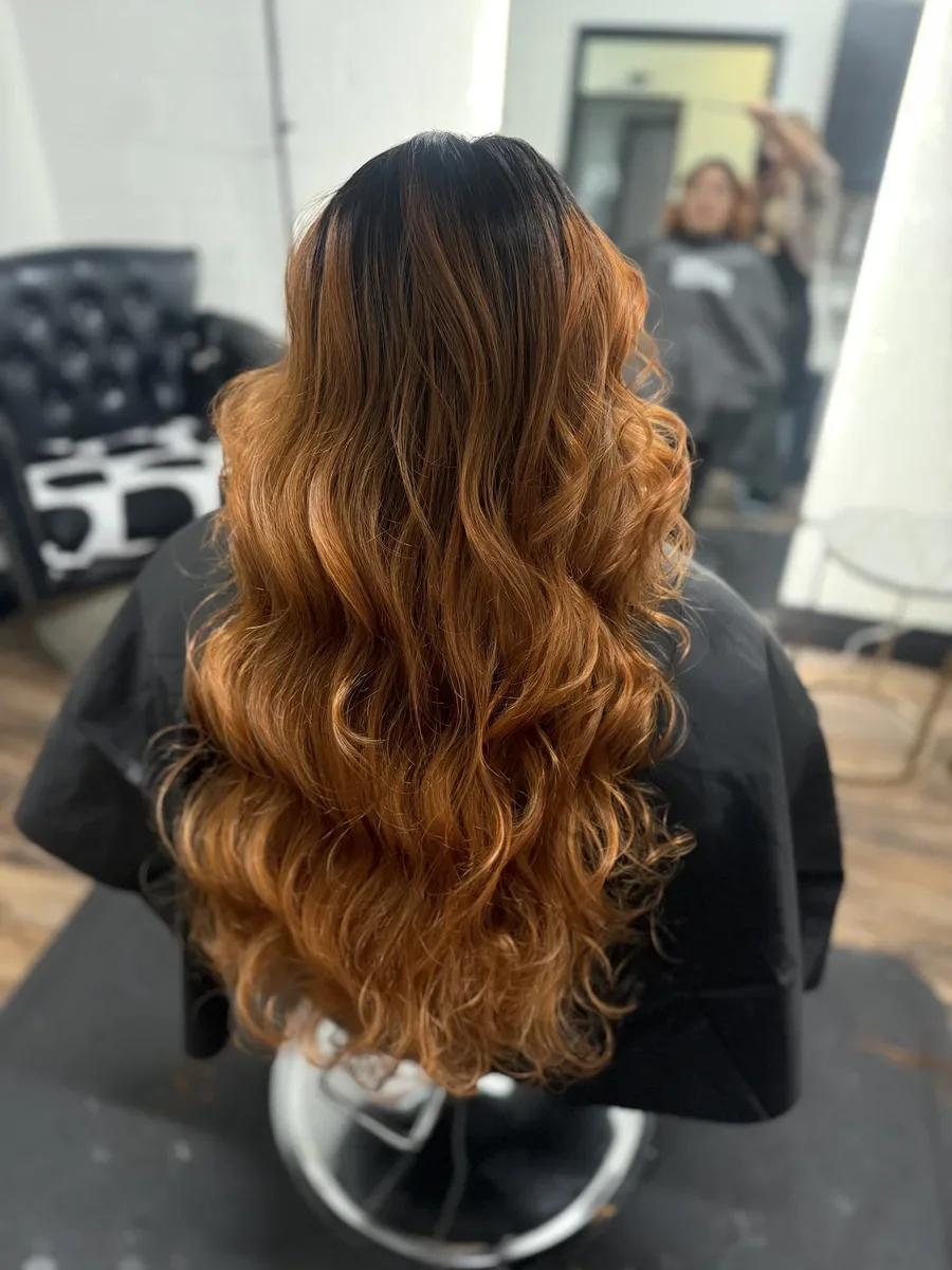 Long copper wavy hair by The Hair Court in Bryan-College Station, TX.