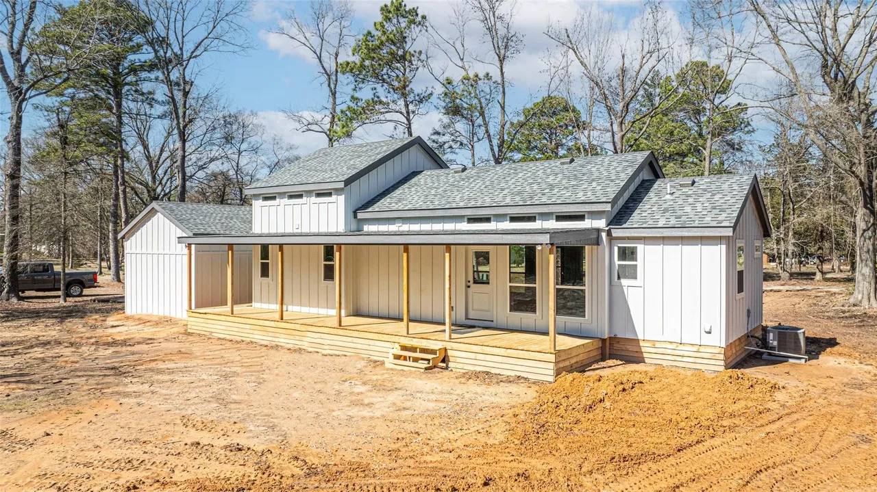 A house under construction with a wooden porch in a wooded area.