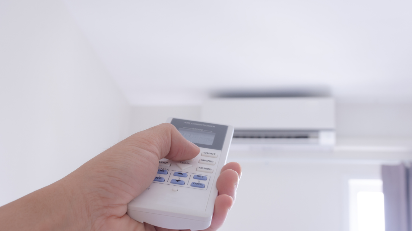 An air conditioning expert adjusting the settings on a remote control of an air conditioner unit at home in Bendigo
