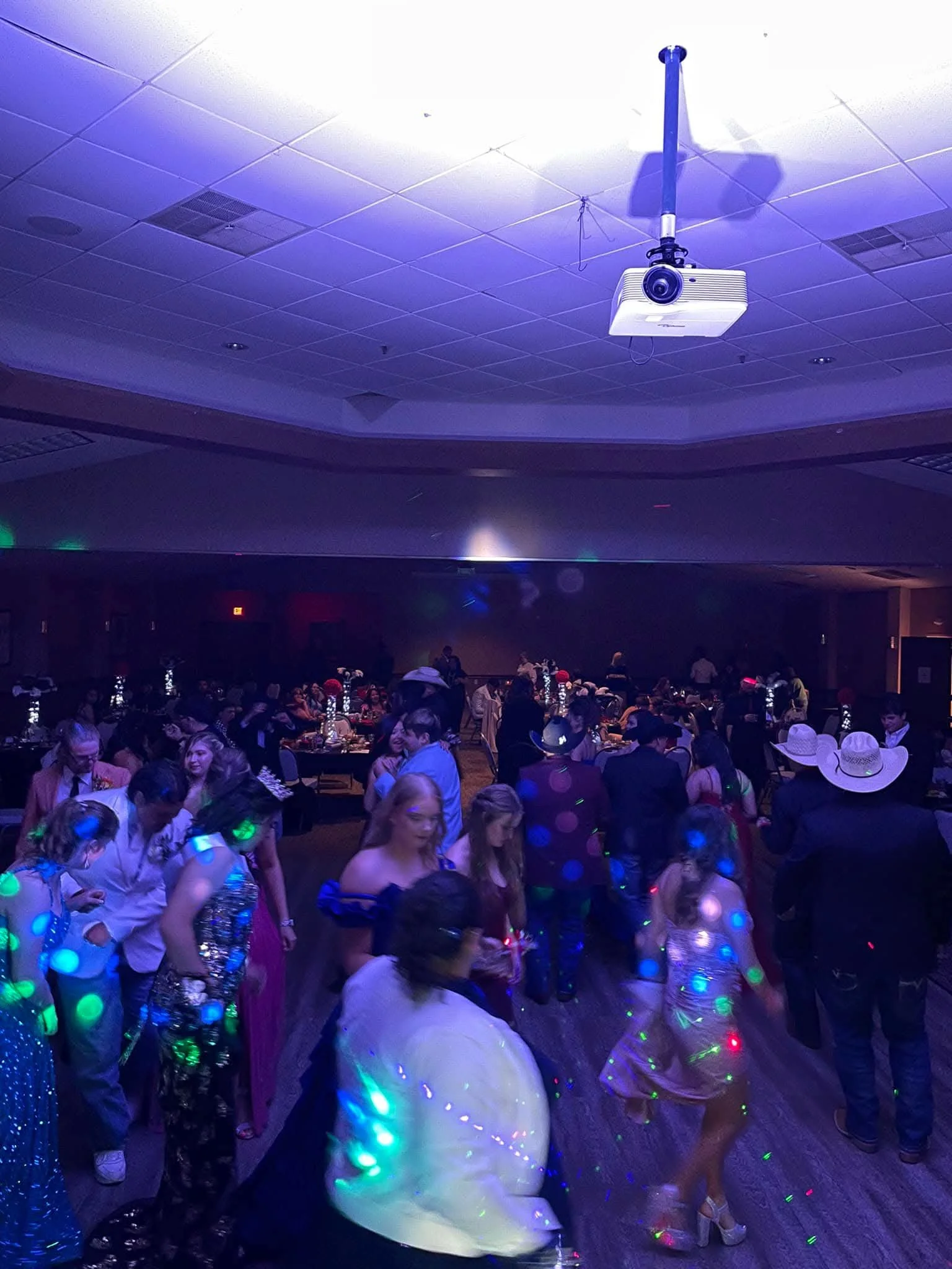 A lively indoor party reception with guests dancing under purple venue lighting in Lubbock Texas
