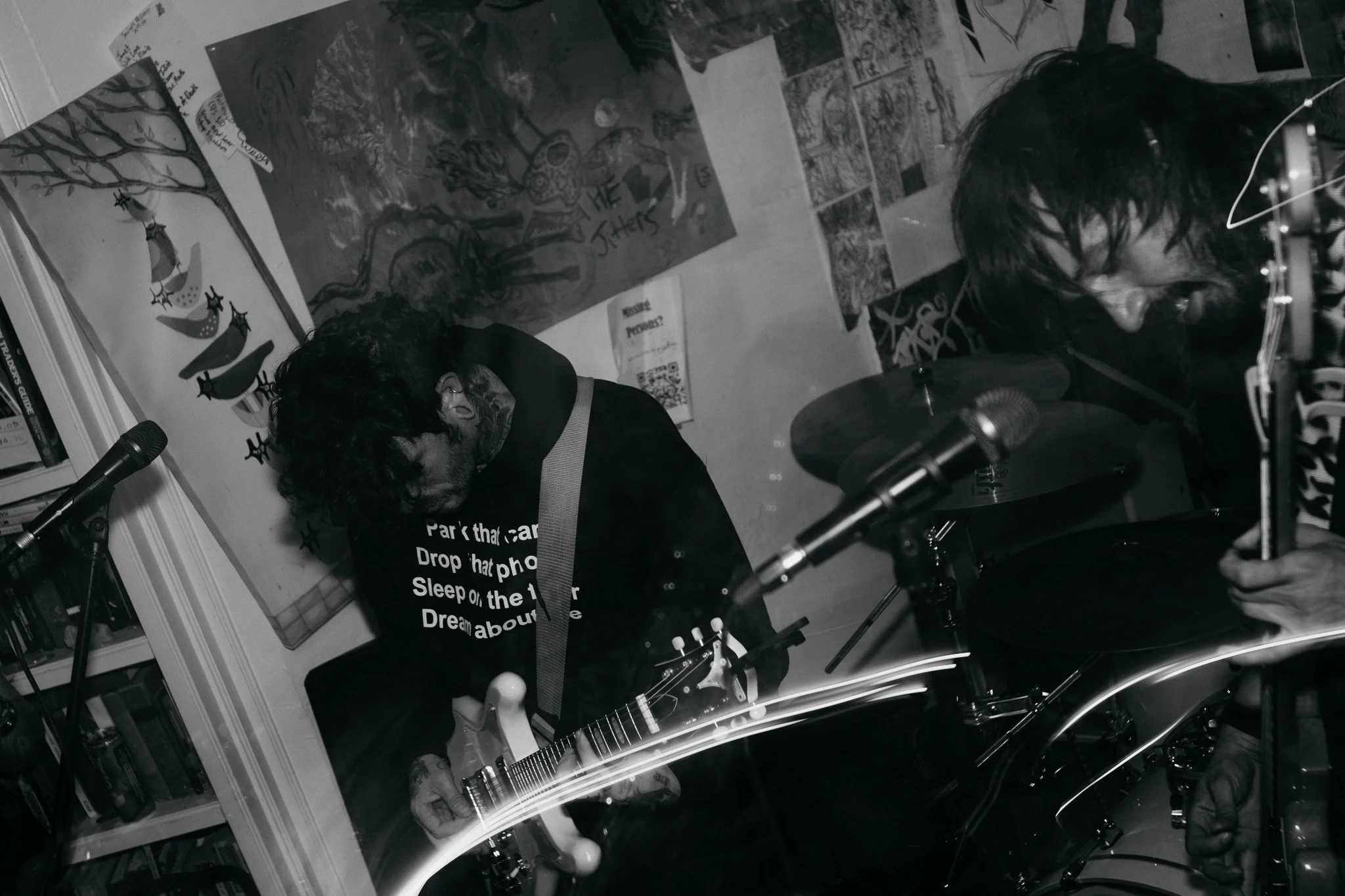 A black and white concert photograph of an underground band performing live with a guitarist and bassist playing intensely in Lubbock Texas