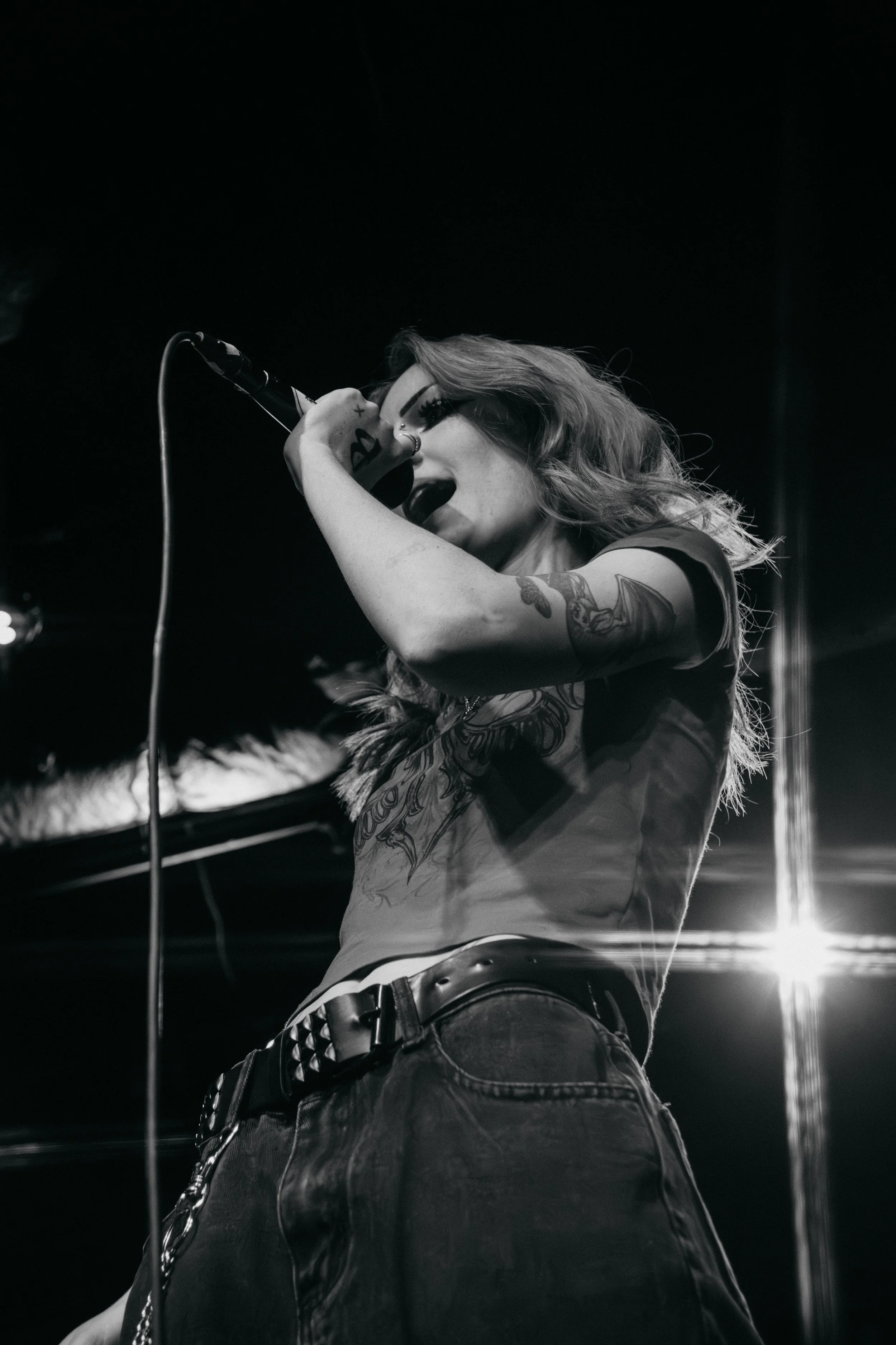 A black and white close up portrait of a passionate female vocalist singing into a microphone on stage during a live concert in Lubbock Texas