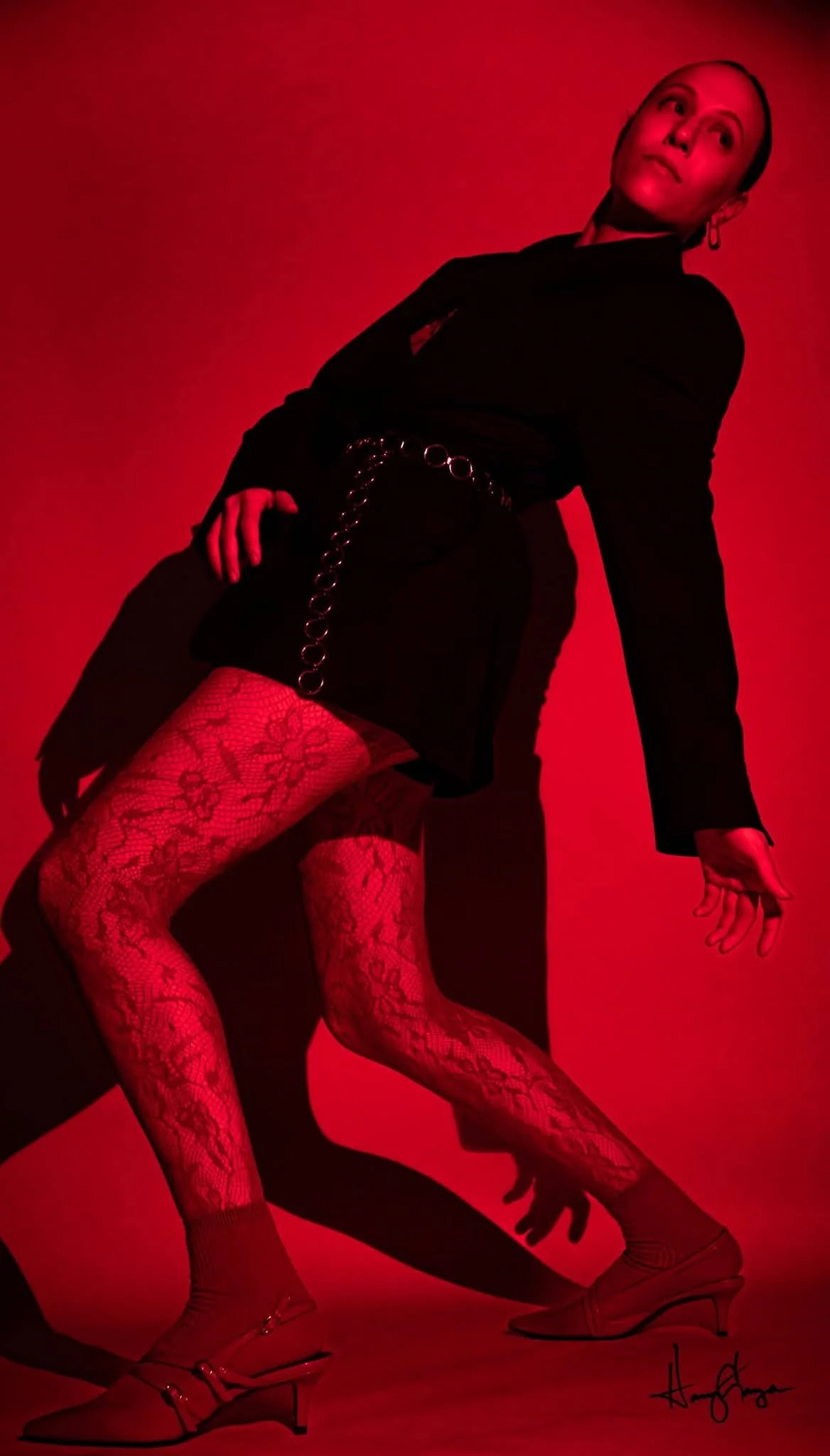 A creative portrait of a woman posing under dramatic red lighting against a dark background in Lubbock Texas