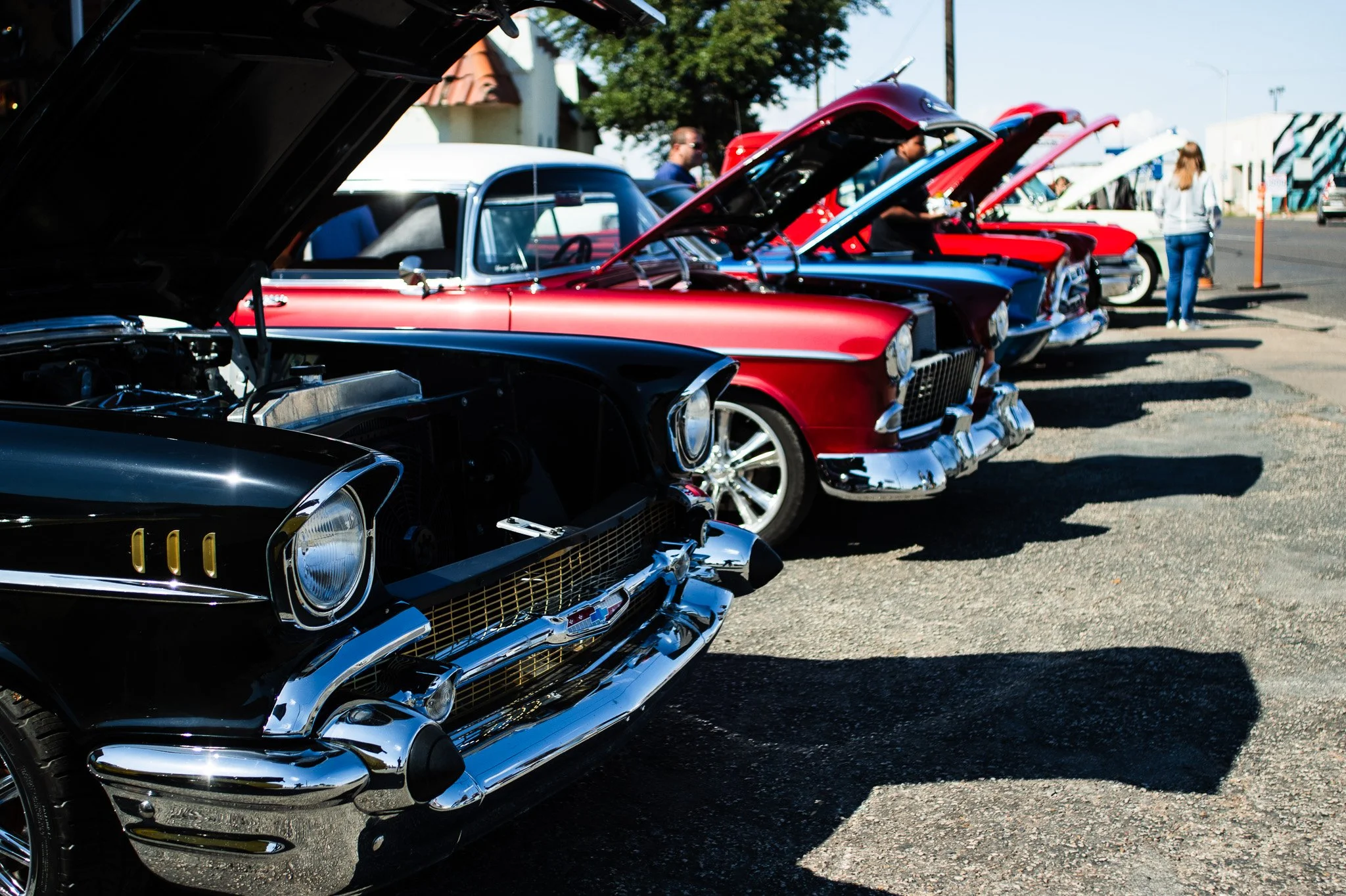 A close up portrait of a pristine classic black 1957 Chevrolet Bel Air with its hood open at an outdoor car show in Midland Texas