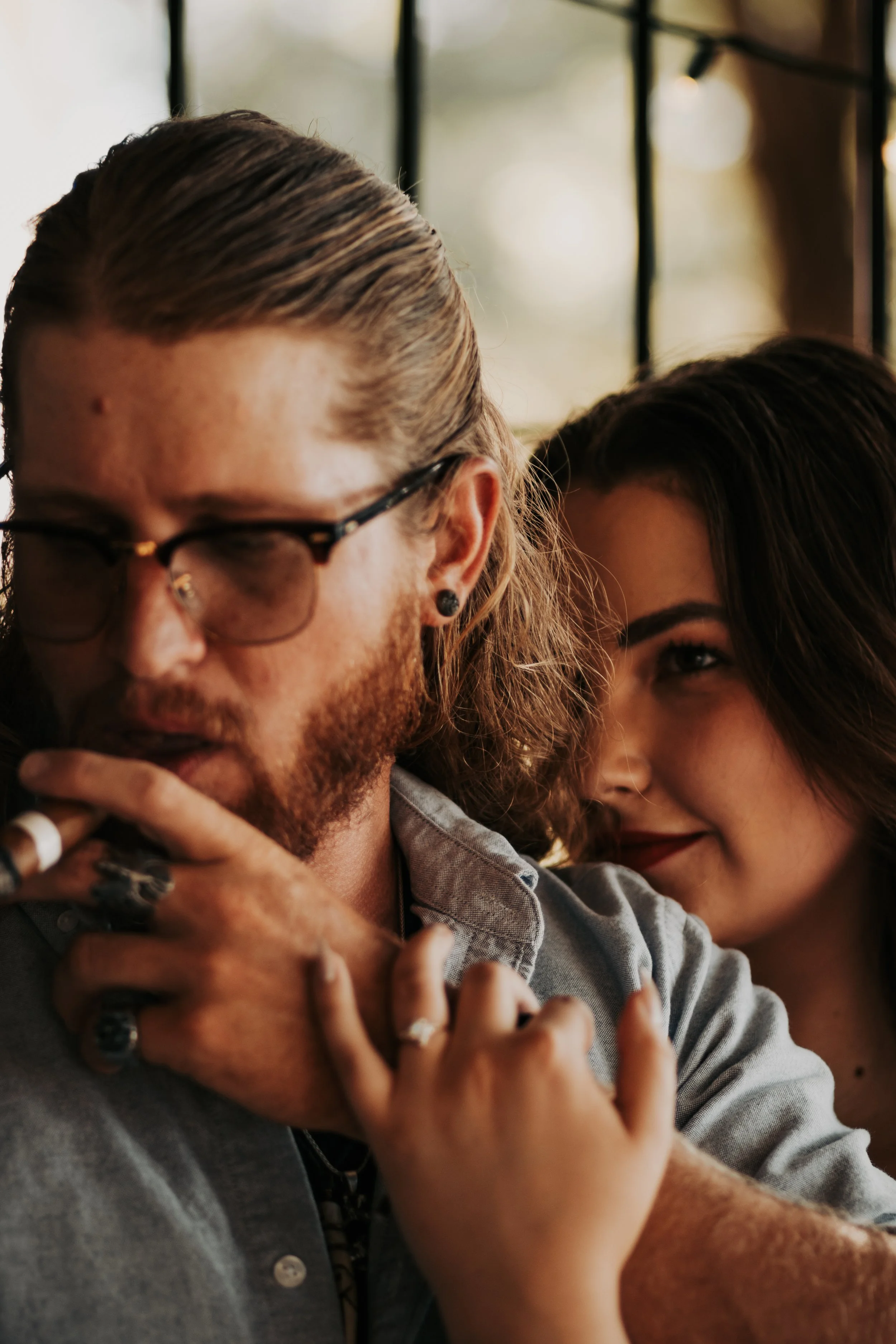 A close up portrait of a man with long hair and glasses holding hands with a smiling woman with dark hair in Lubbock Texas