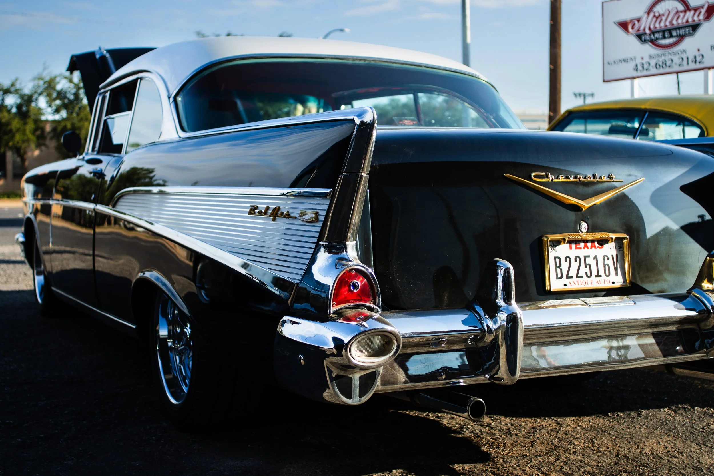 A close up shot highlighting the chrome tail fin and taillight of a classic black 1957 Chevrolet Bel Air with a Texas antique license plate in Lubbock Texas