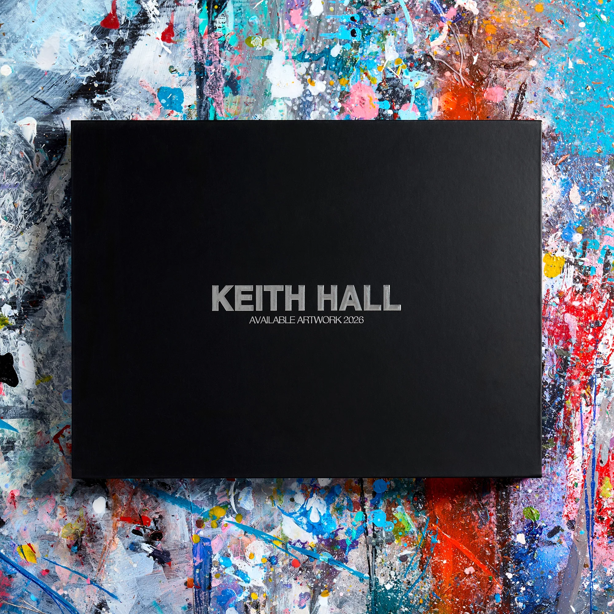 Close-up of a black canvas with the text 'KEITH HAL' and 'AVAILABLE ARTWORK 2026' in silver lettering, placed over a colorful, abstract splatter painting with various bright colors and dynamic brushstrokes.