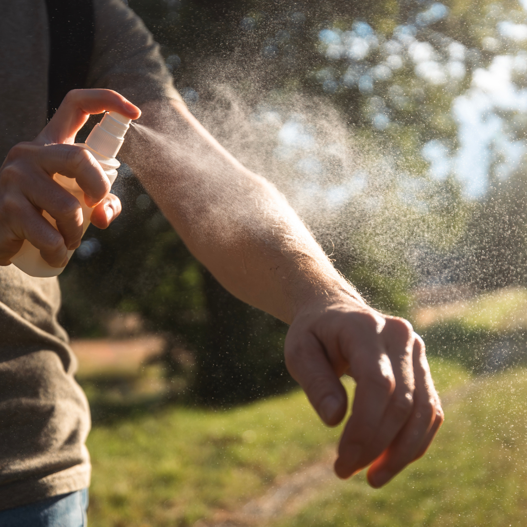 close up of spray being misted on a person's arm with sun filtering