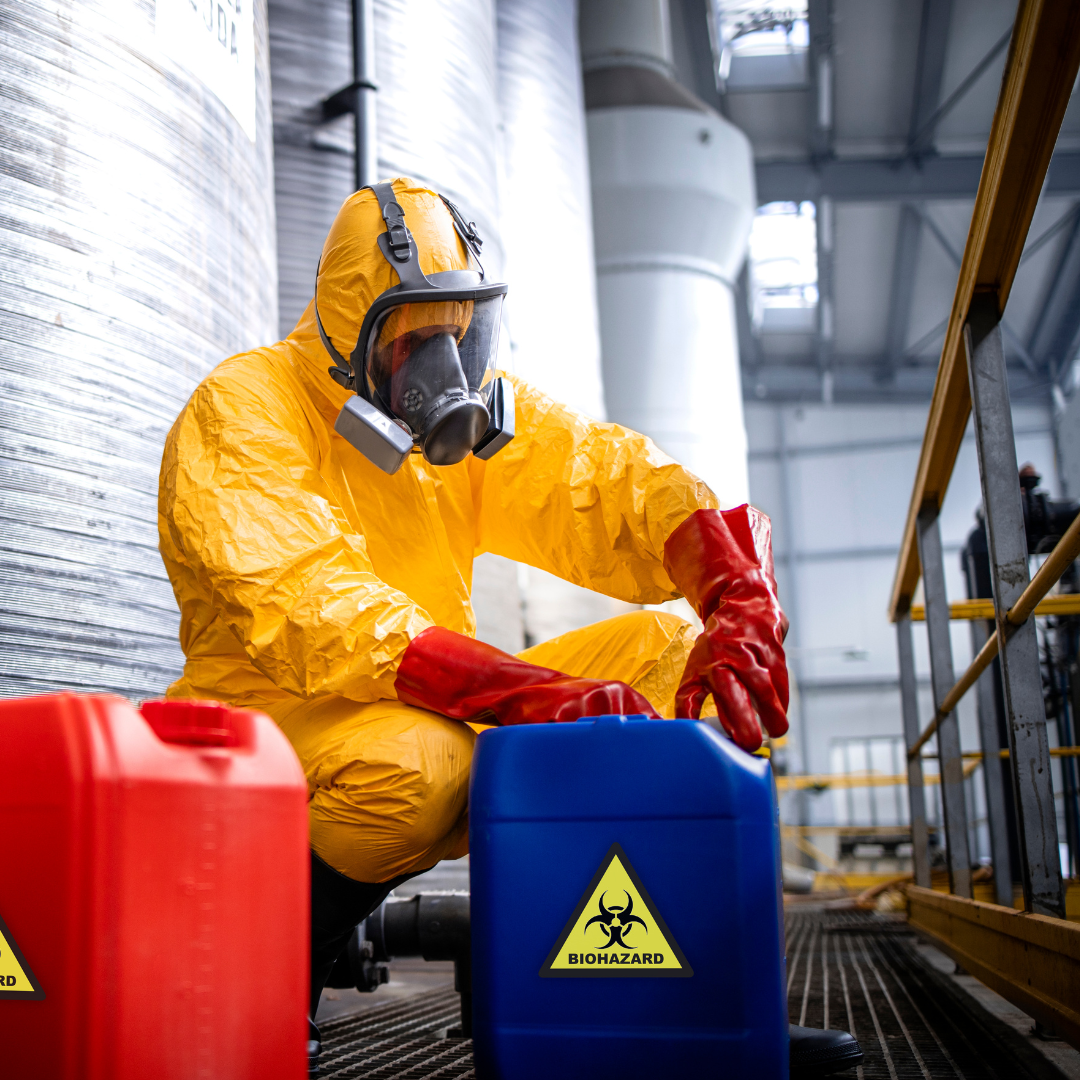 person in hazmat suit opening a large container of of something labeled biohazard