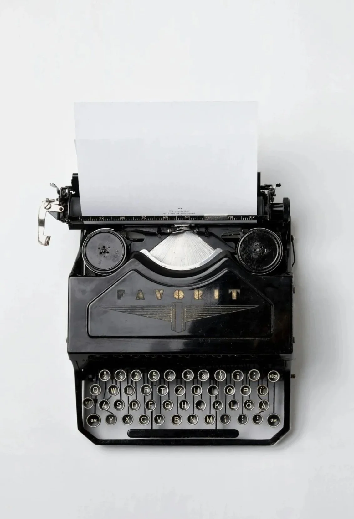 Vintage black typewriter with white sheet of paper, set against a plain white background.