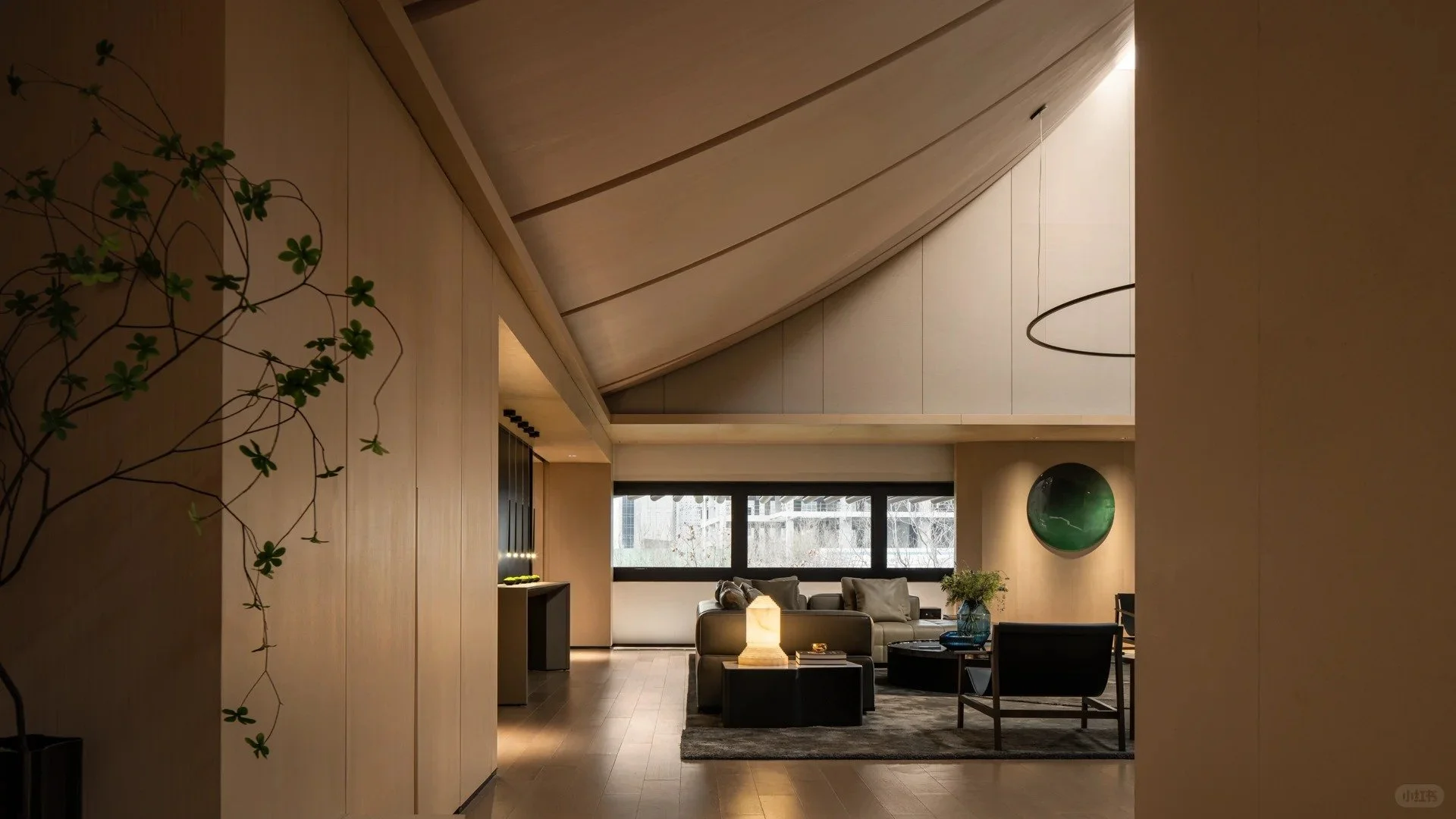 Modern living room with wooden walls, sloped ceiling, black-framed window, a green decorative orb on the wall, and a seating area with couches, chairs, a lamp, and a plant.