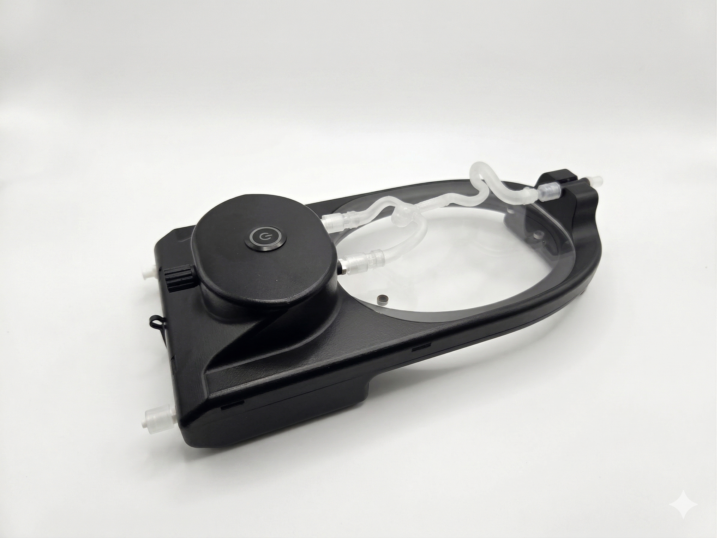 A black medical device with tubing and a power button on top, placed on a white surface.