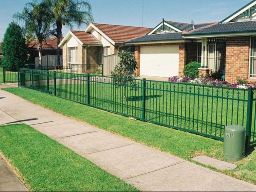 Neatly manicured front yard with a green powdercoated fence installed by SWIFT Powdercoating