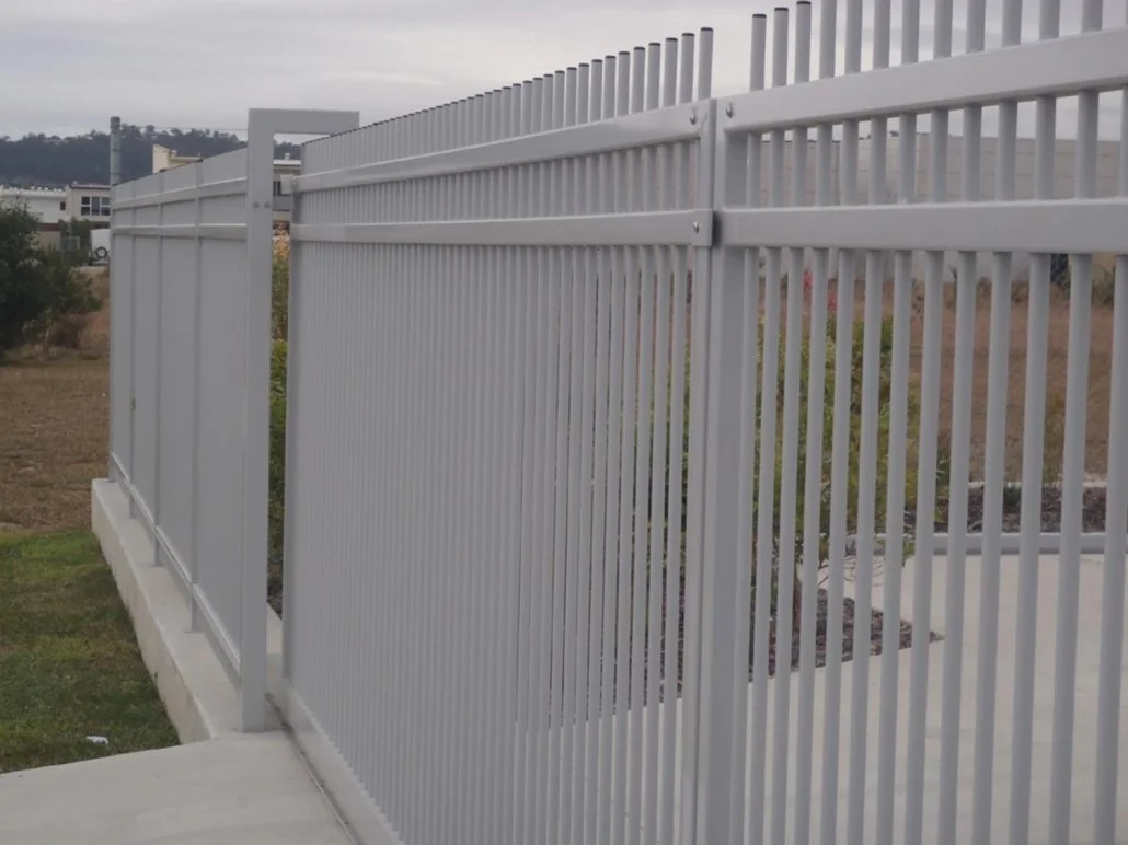 White powdercoated aluminium fence with vertical bars and a sliding gate on concrete - manufactured and installed by Swift Powdercoating & Fencing Brisbane