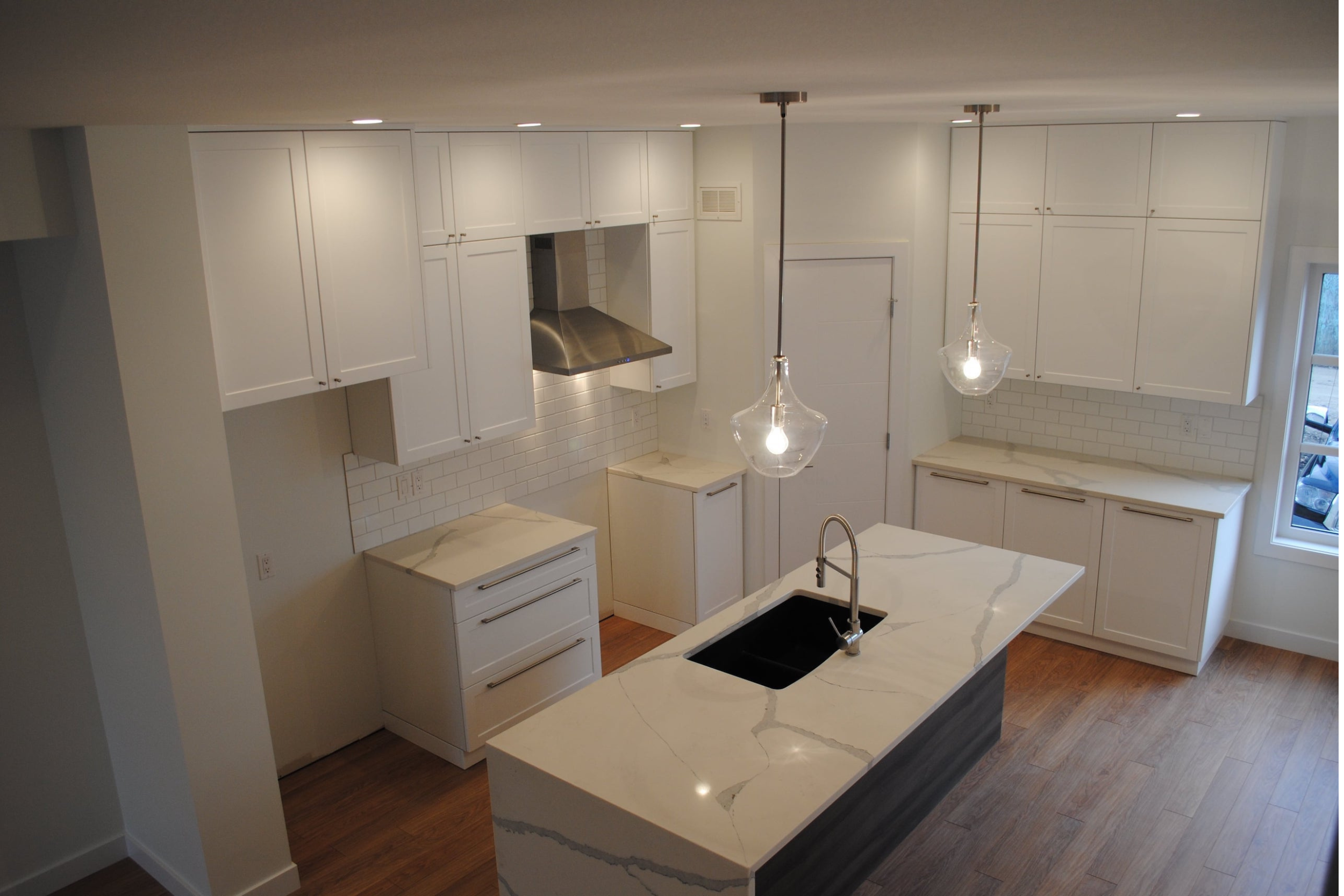 Modern kitchen with white cabinets, marble countertops, and pendant lights