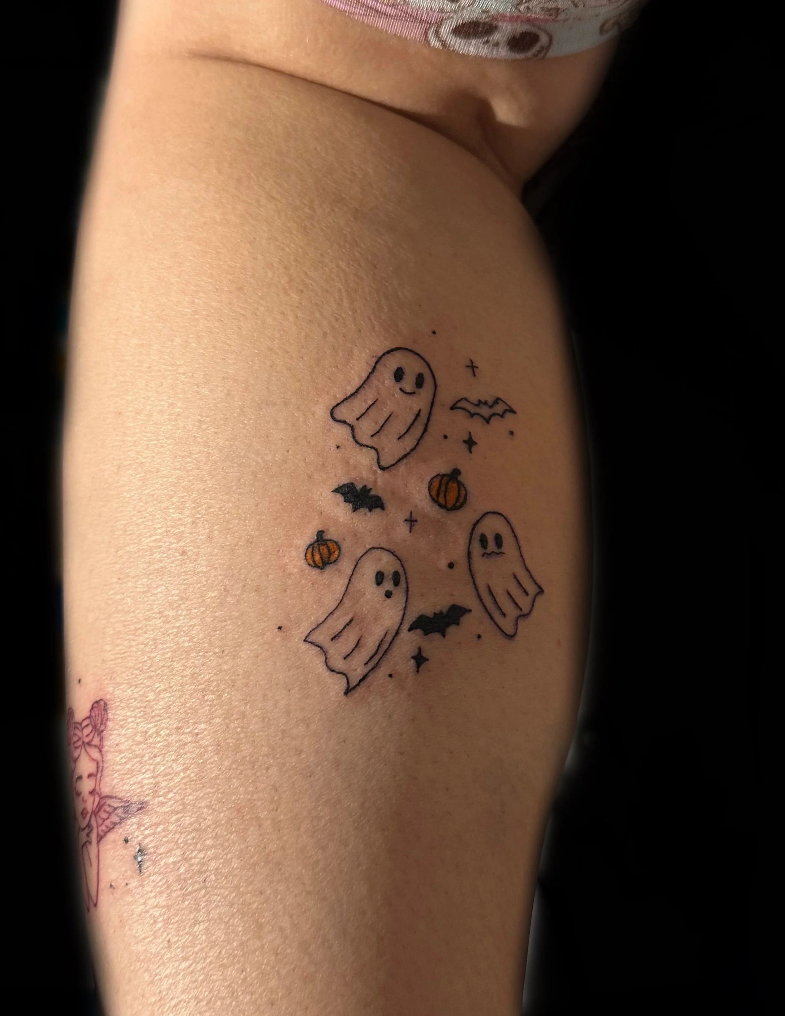 Tattoo of cute ghosts, pumpkins, bats, and stars on person's skin.