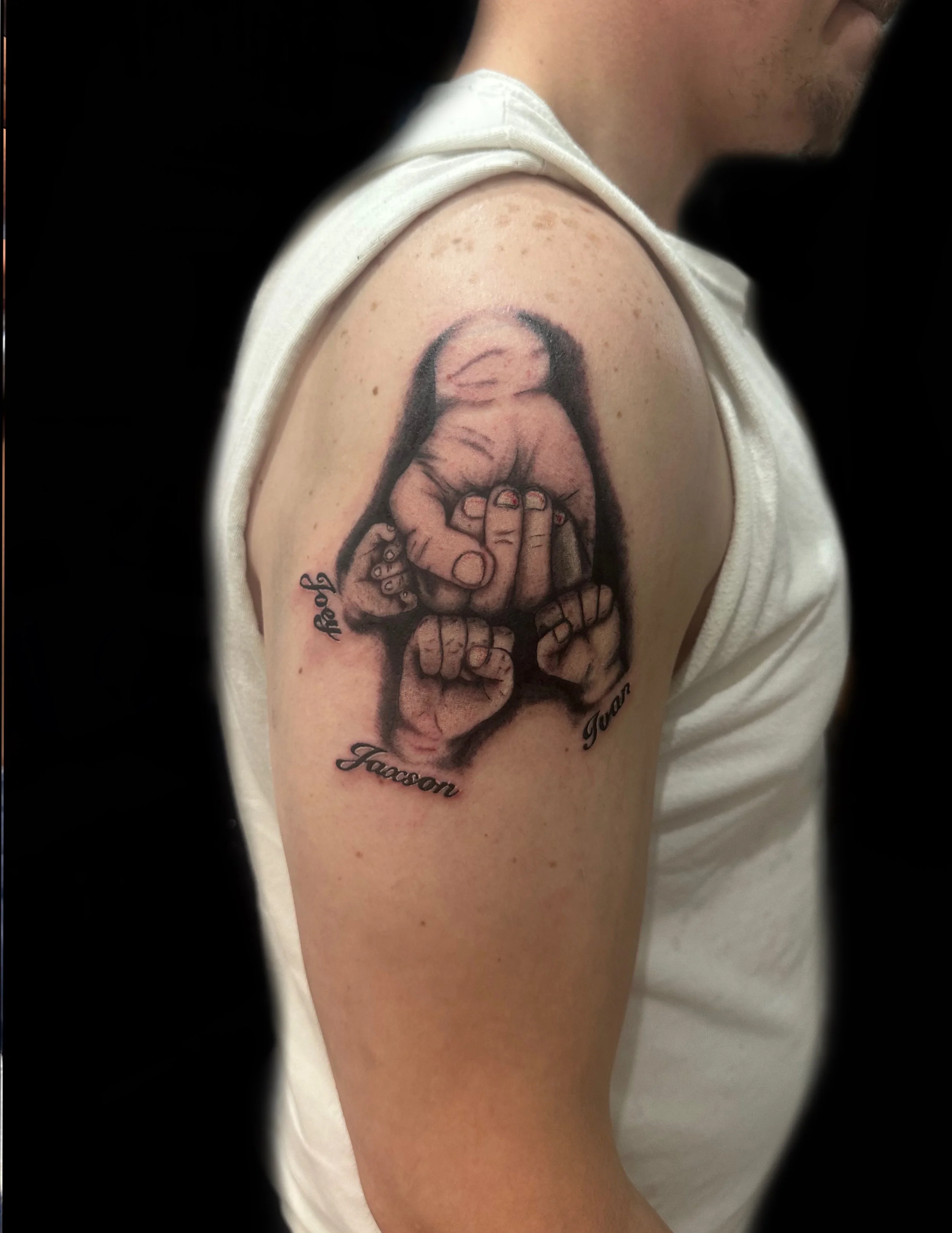 Four sets of hands, father, two boys and his little girls fists all fist bumping together tattooed on the arm.