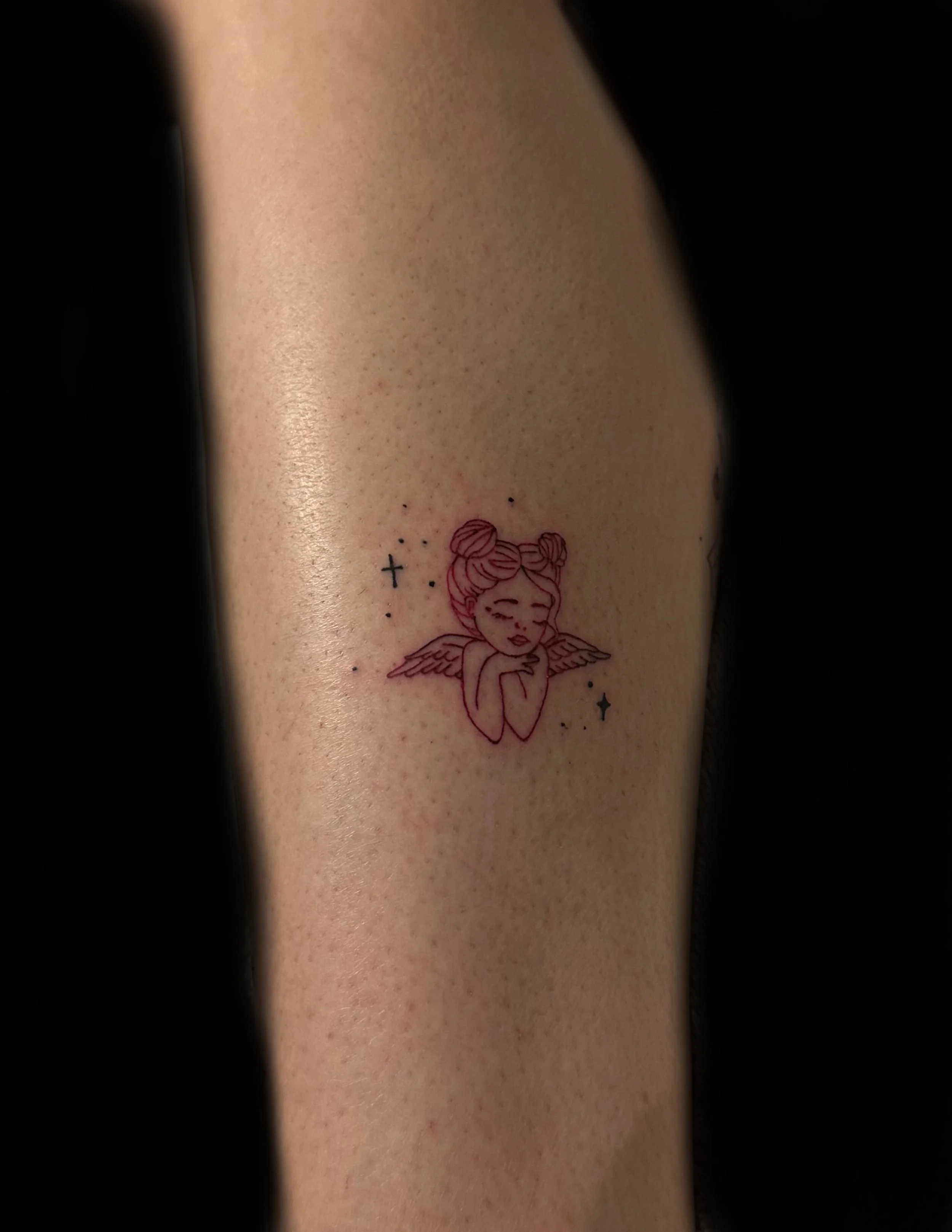 Tattoo of a girl with angel wings, her eyes closed, on person's arm.