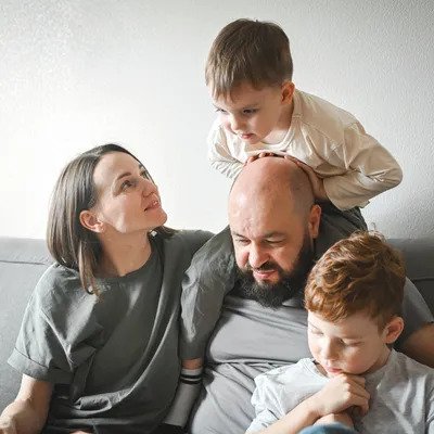 A family with a mother, father, and two children sitting together on a couch, smiling and enjoying each other's company.